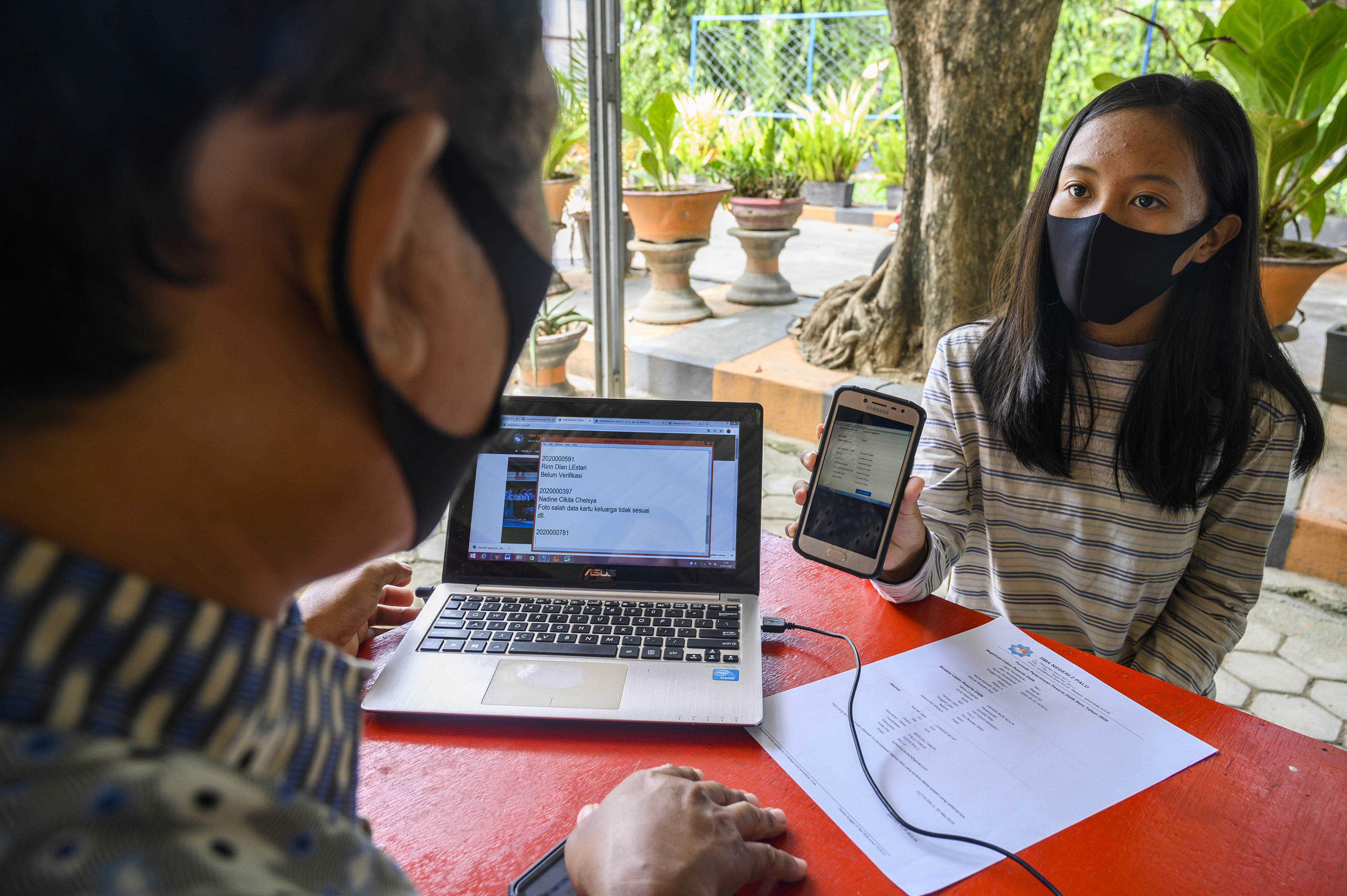 Seorang staf sekolah memverifikasi berkas administrasi peserta didik baru yang terdaftar secara daring di SMA Negeri 2 Palu, Sulteng.