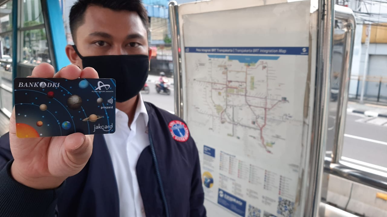 Pengguna transportasi menunjukan JakCard sebagai alat pembayaran non tunai. 