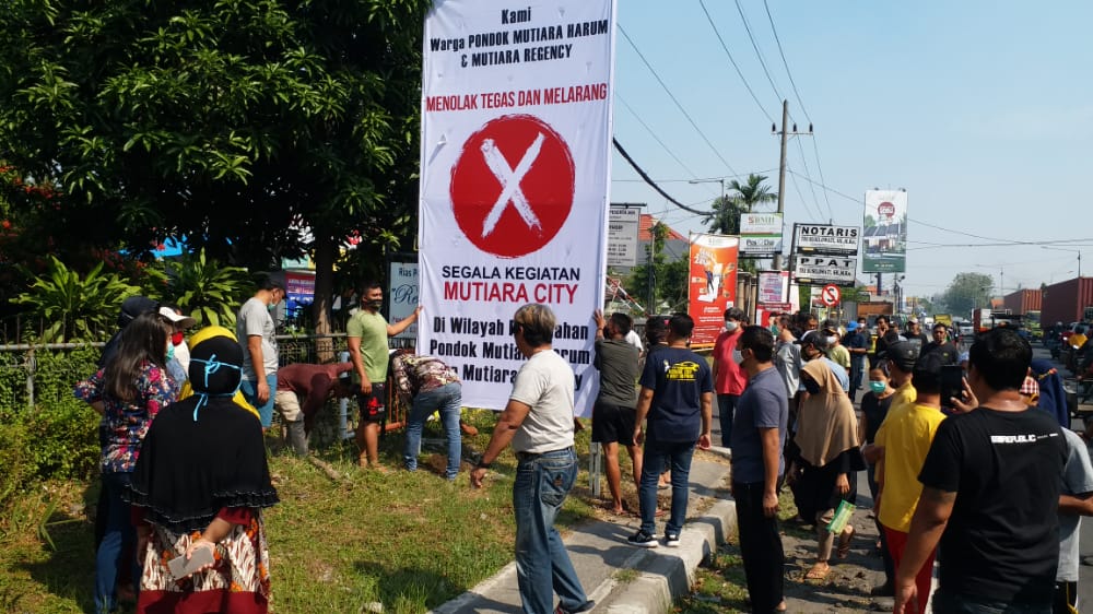 Warga memasang banner di depan pintu masuk perumahan Jalan Raya Jati Kecamatan Sidoarjo Kabupaten Sidoarjo, Sabtu (27/6/2020).