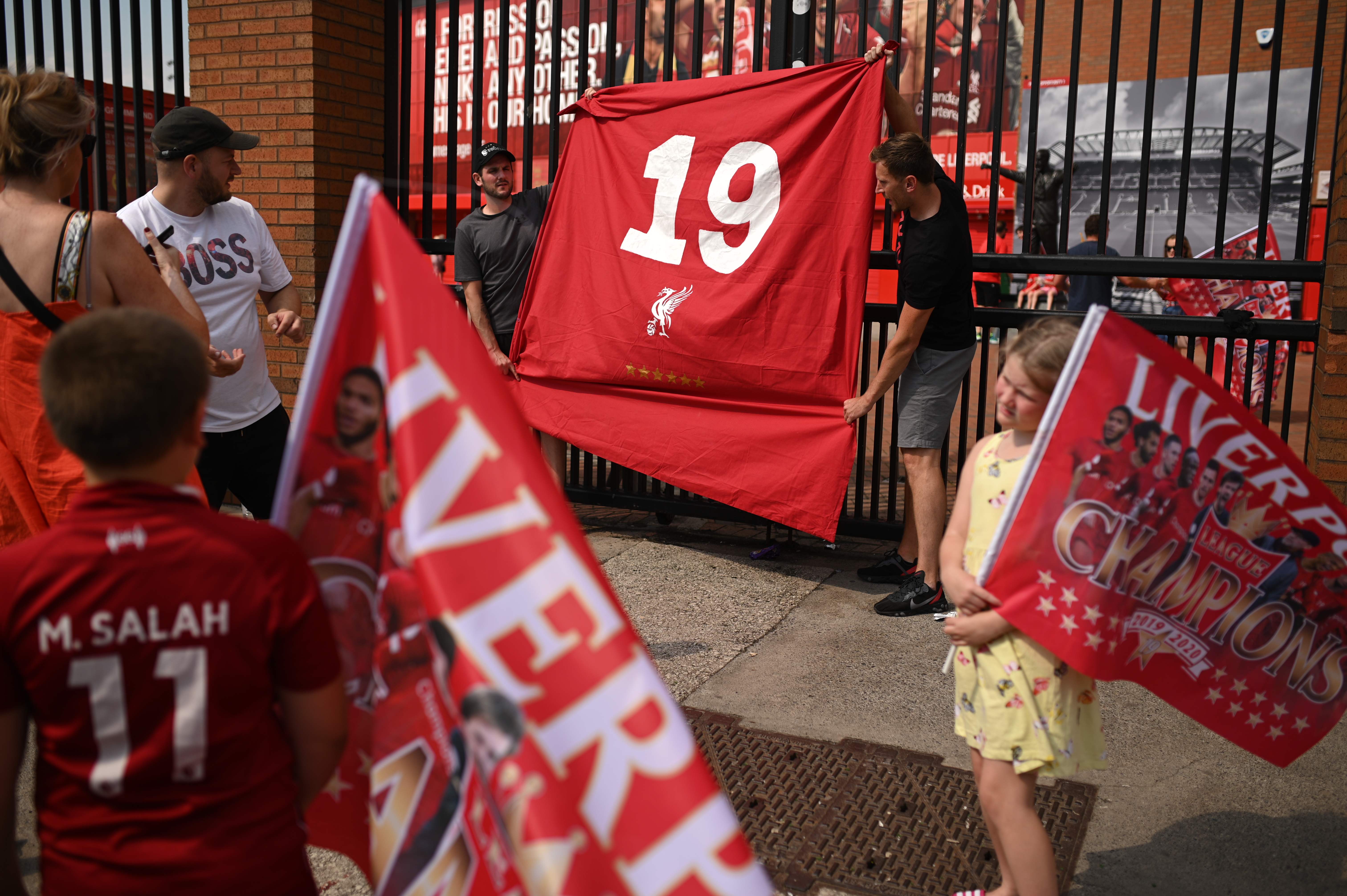 Pendukung Liverpool membentangkan bendera nomor 19 yang merupakan simbol kemenangan ke-19 kali mereka Juara EPL di depan Stadion Anfield.