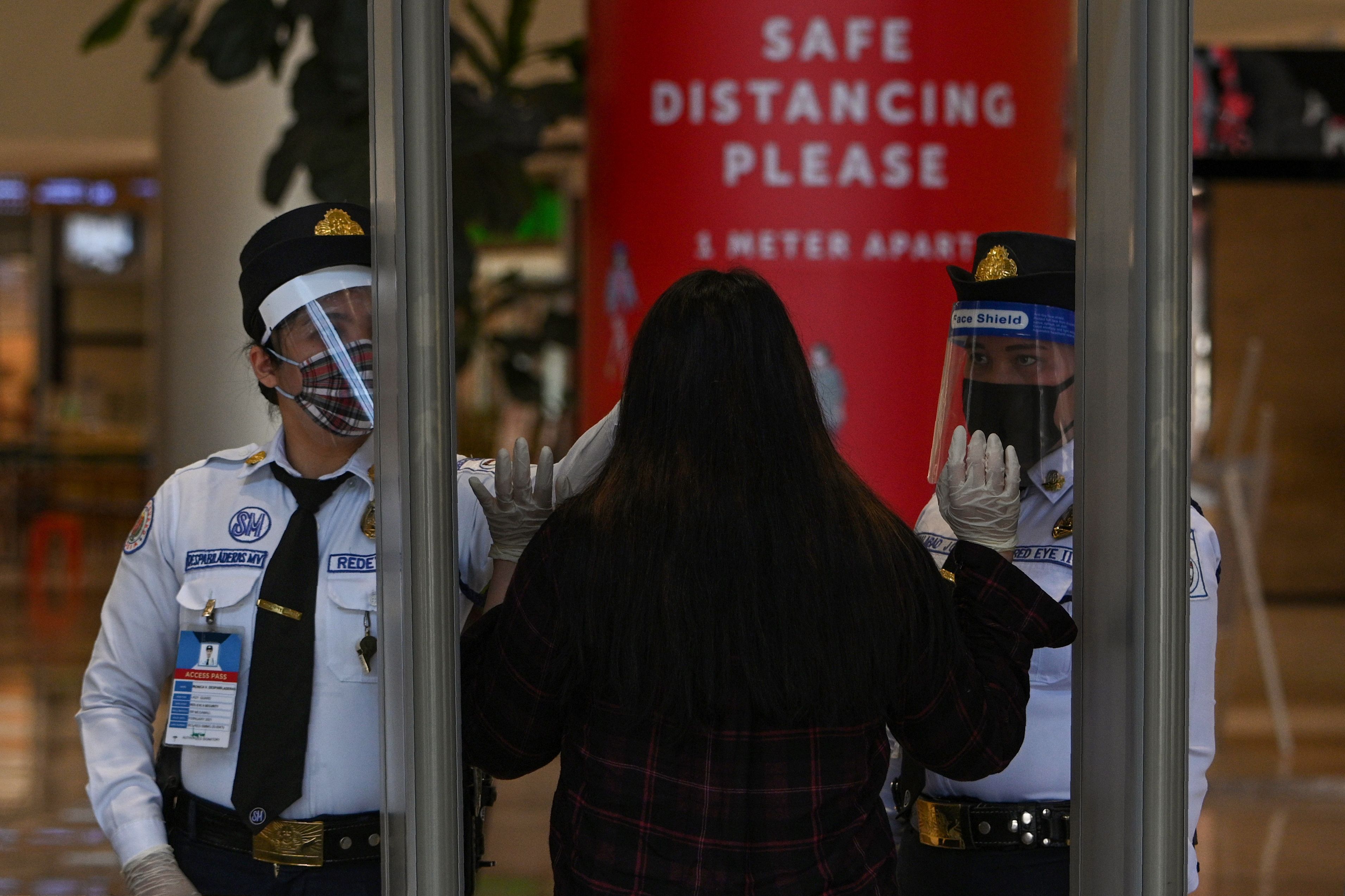 Petugas di pusat perbelanjaan Manila memeriksa suhu tubuh pengunjung.