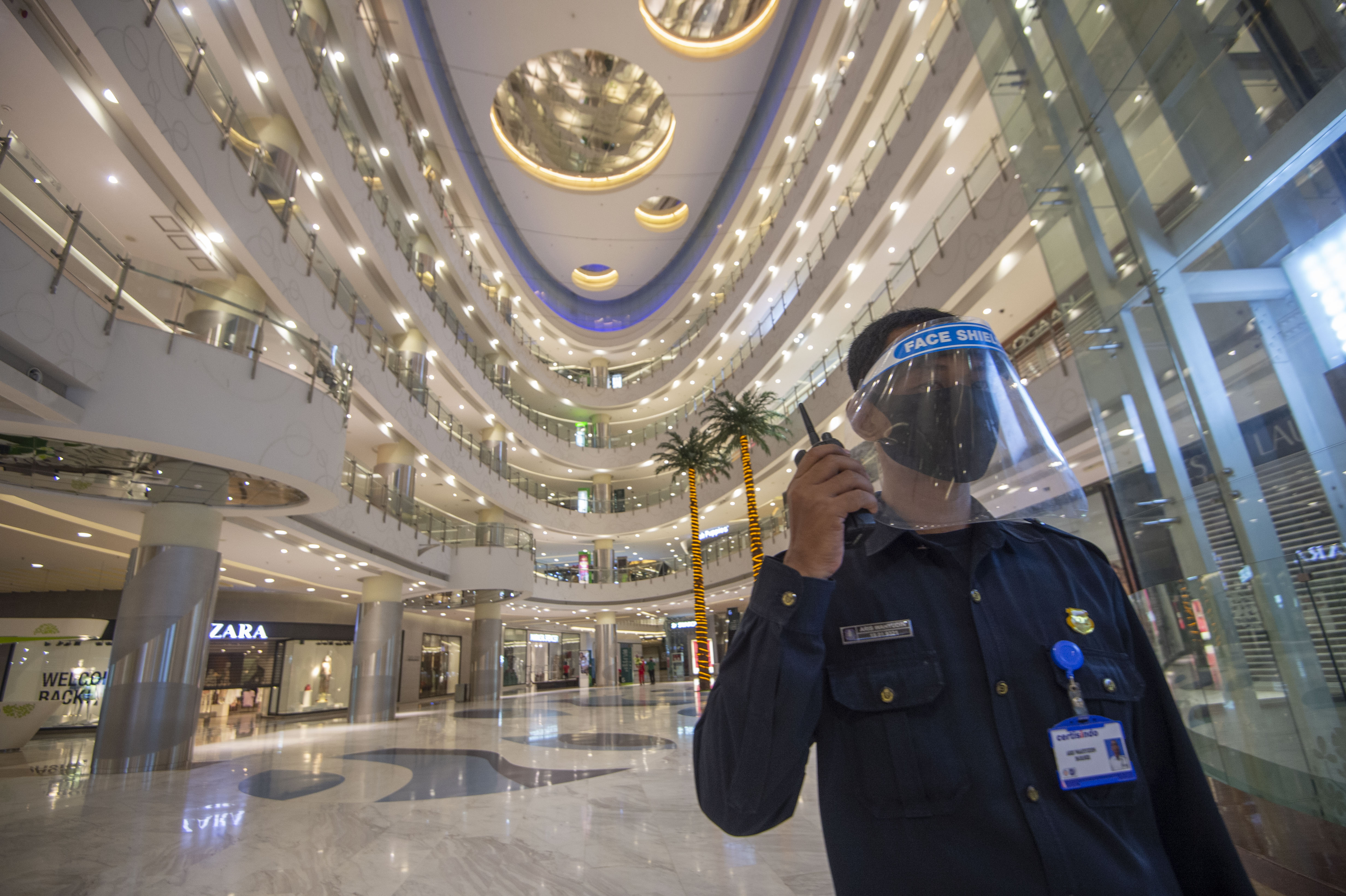 Petugas keamanan di Mal Central Park mengenakan masker dan pelindung wajah.