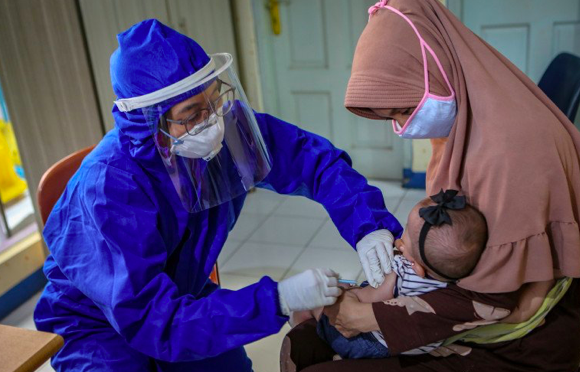 Petugas menggunakan alat pelindung diri (APD) memberikan imunsiasi kepada balita di Puskesmas Karawaci Baru, Kota Tangerang, Banten.