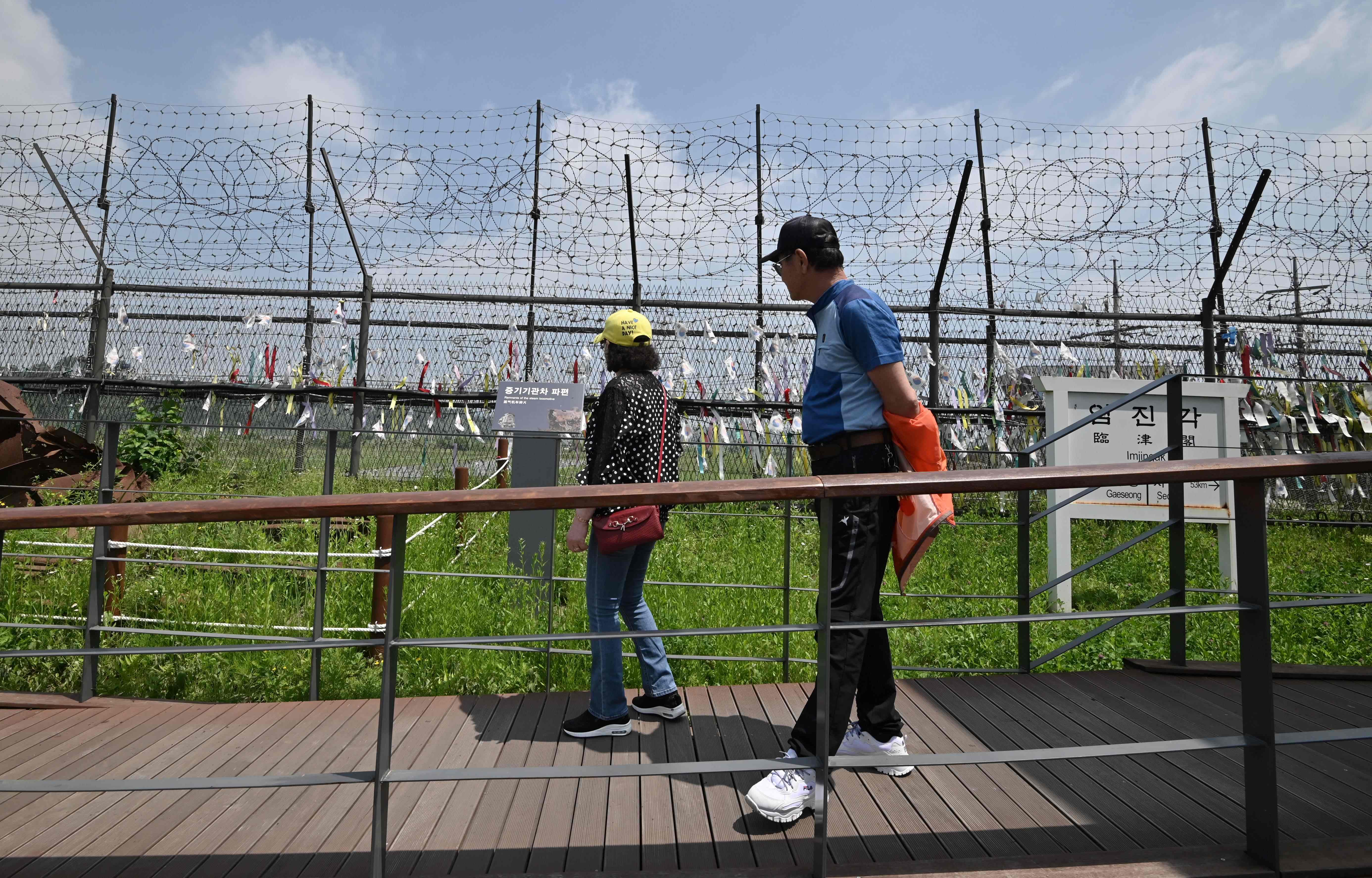 Pengunjung berjalan di sepanjang pagar militer yang dihiasi dengan pita di di taman perdamaian Imjingak, dekat Zona Demiliterisasi (DMZ).