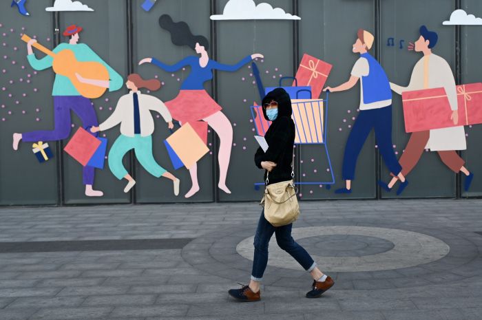 Seorang Tiongkok warga melintas di jalan di Beijing dengan mengenakan masker. 