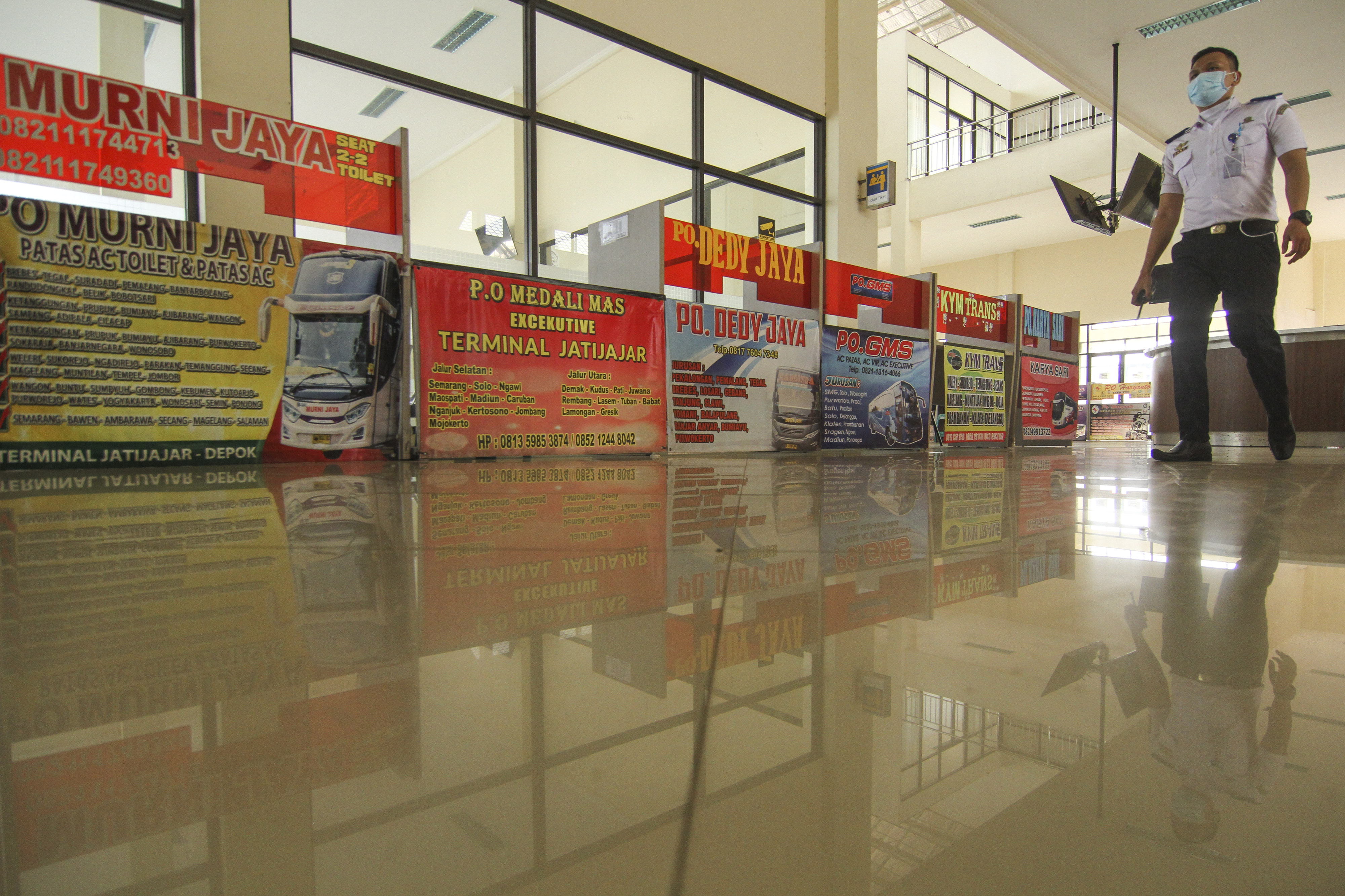 Petugas keamanan berjalan di depan loket pembelian tiket di Terminal Jatijajar, Depok, Jawa Barat, Jumat (12/6).