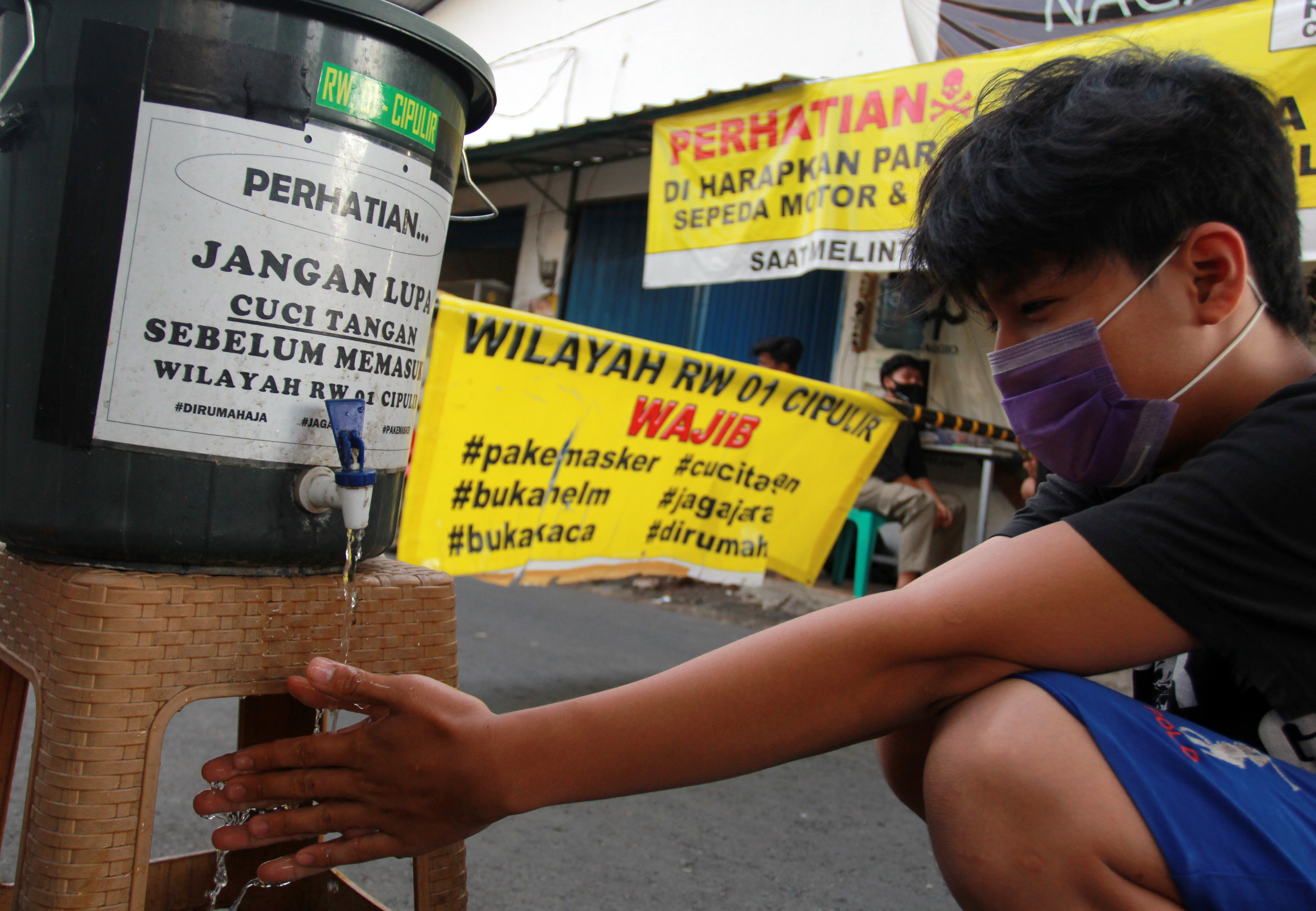 Warga mencuci tangan sebelum masuk ke perkampungan yang melakukan karantina wilayah, di Cipulir, Jakarta Selatan, Selasa (2/6/2020). 