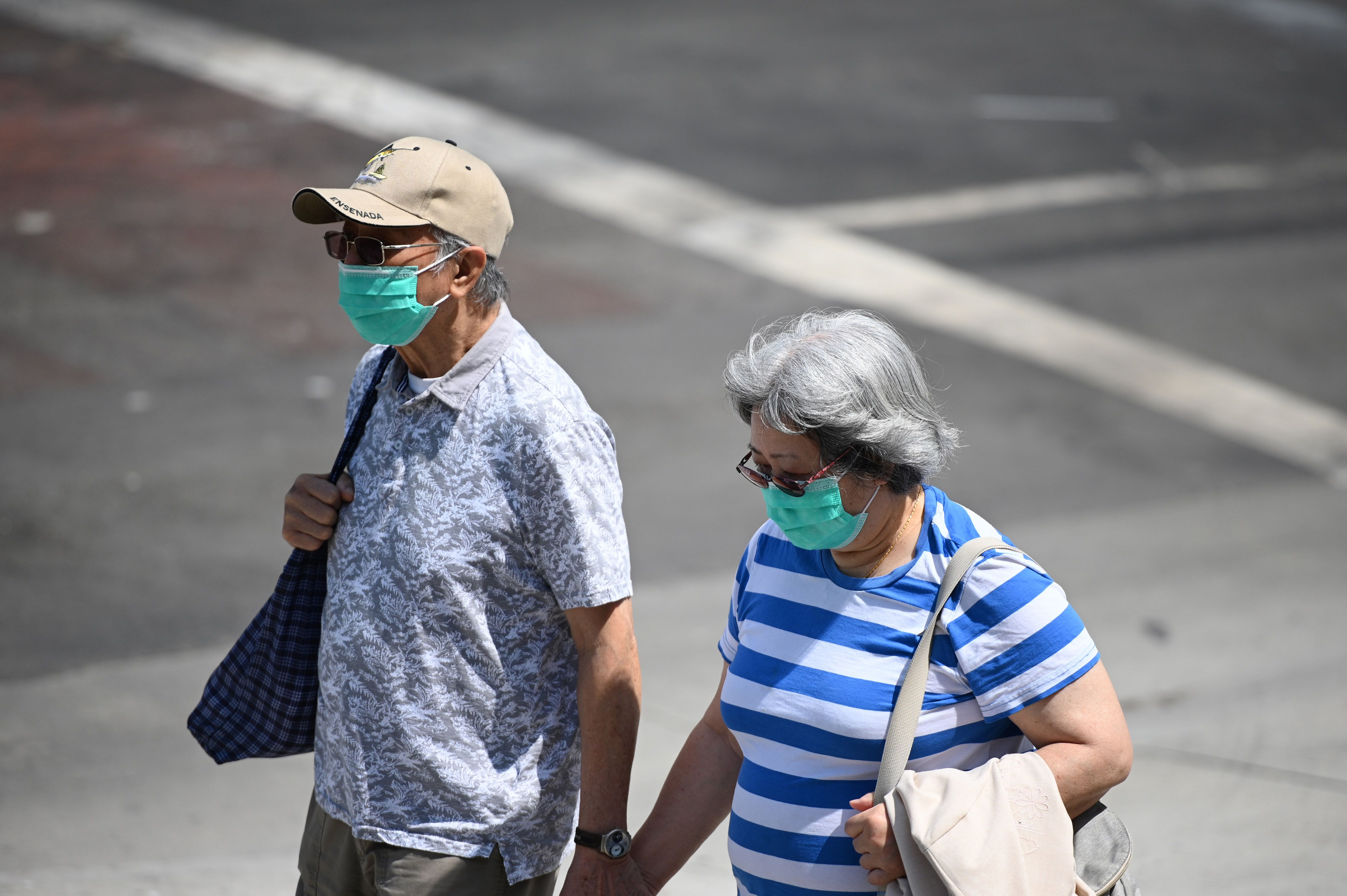Sepasang suami istri memakai masker berjalan beriringan di pusat kota Los Angeles, California, Rabu (24/6).