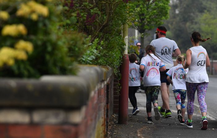  Sebuah keluarga yang mengenakan kaos bergambar pelangi yang dijadikan simbol harapan selama pandemi covid-19 berlari di Southport, Inggris.