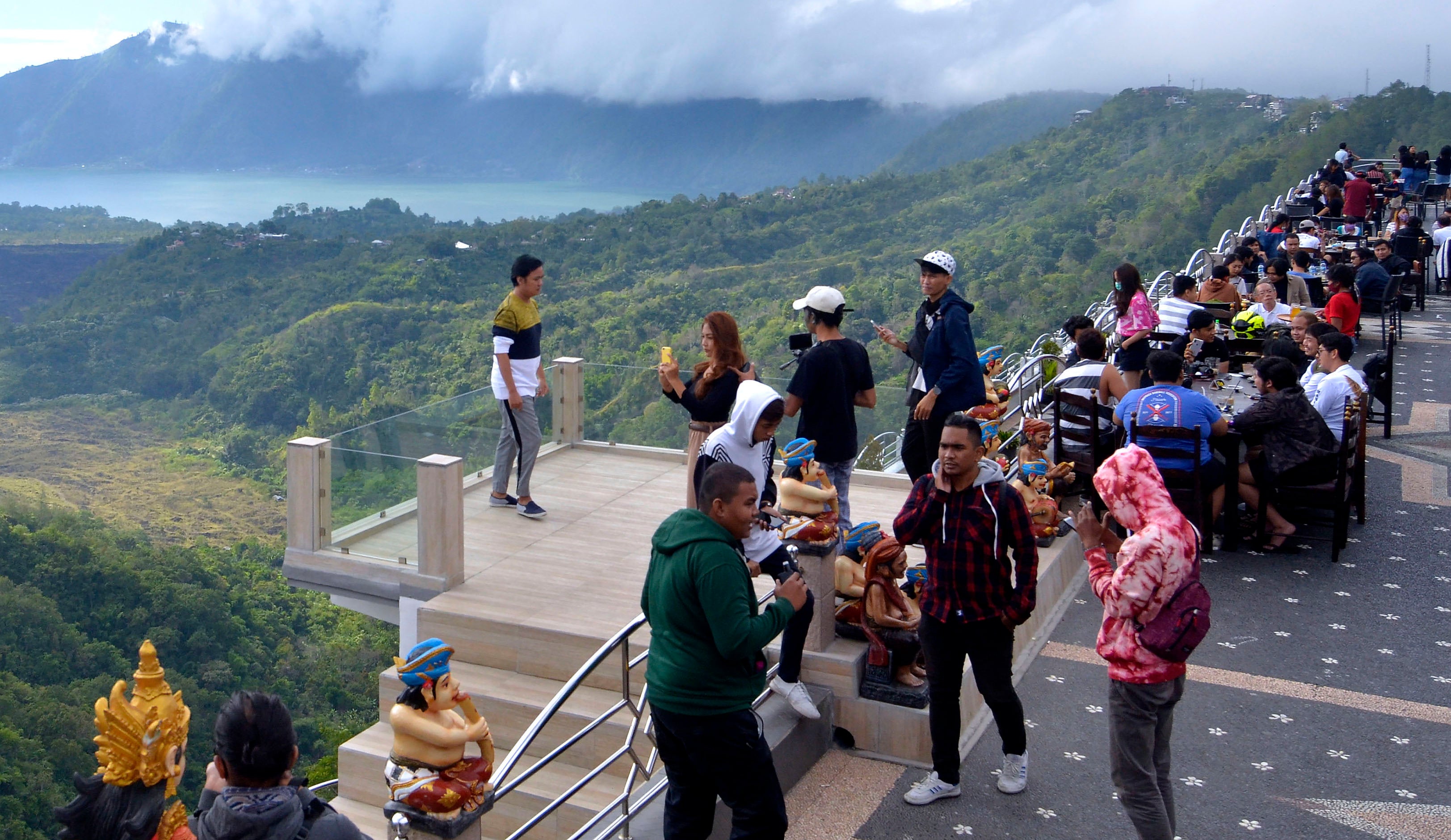 Wisatawan menikmati pemandangan alam Danau Batur dari sebuah restoran di kawasan Kintamani, Bangli, Bali, Minggu (21/6)