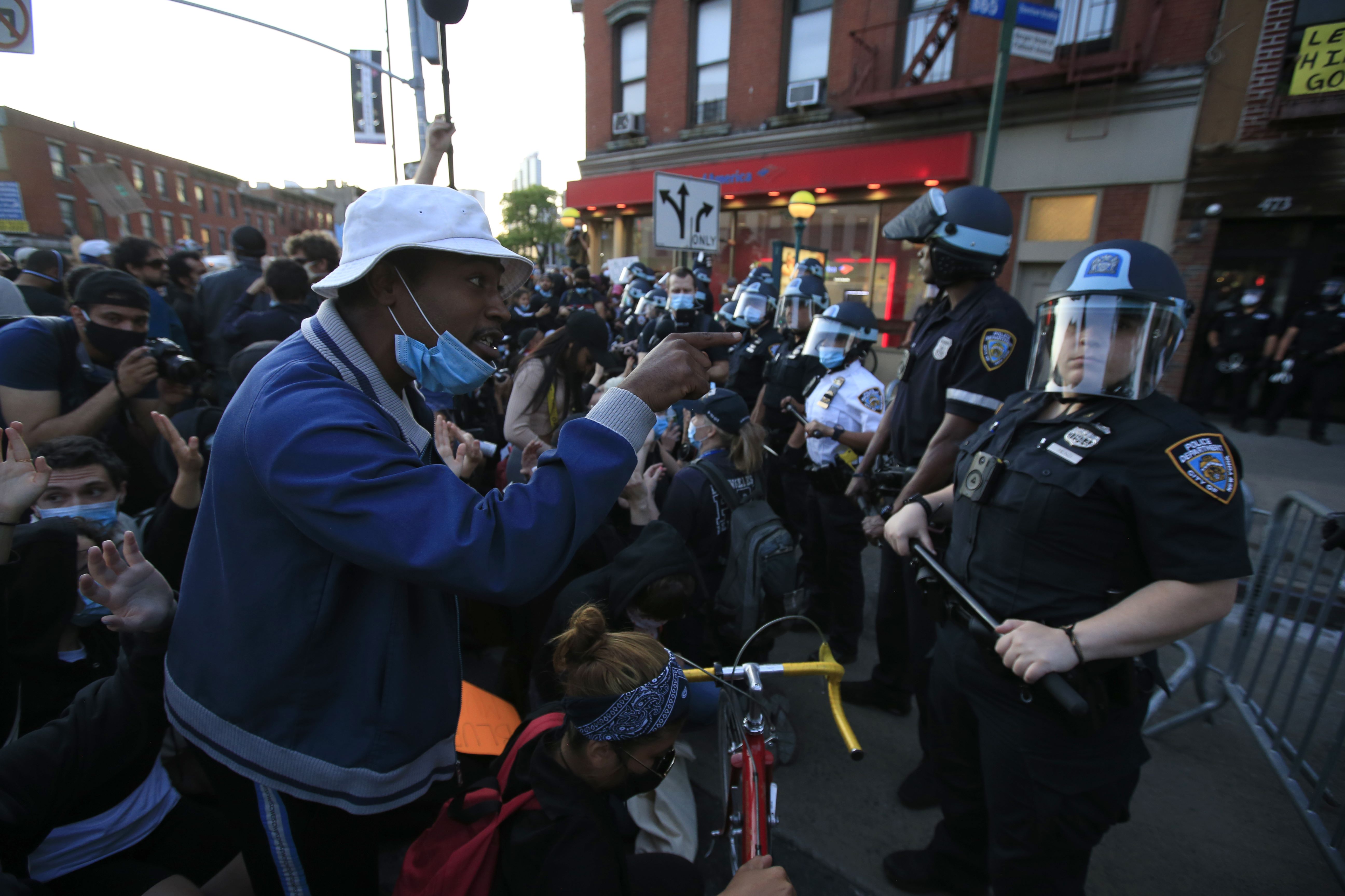 Seorang pria berbicara dengan seorang perwira polisi saat unjuk rasa atas kematian George Floyd di Brooklyn, Kota New York, AS, Minggu (31/5