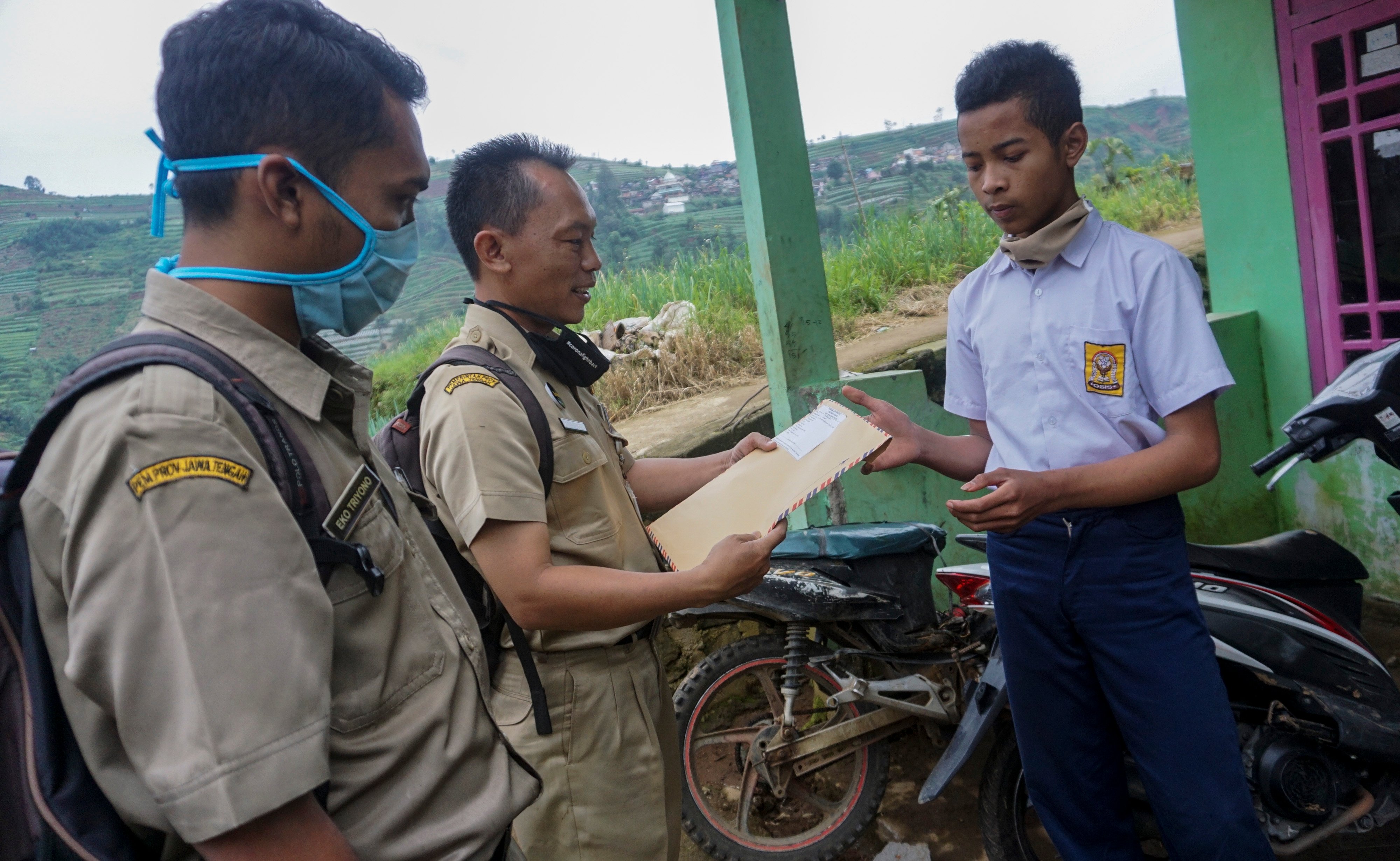 Kepala sekolah SMP N 4 Bawang Mulud Sugito (tengah) bersama guru wiyata menyerahkan lembar tugas soal kepada siswa yang belajar di rumah