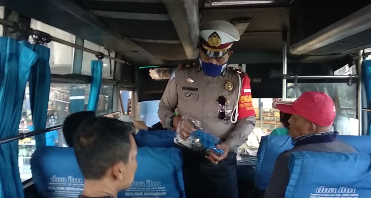 Anggota Polres Tasikmalaya Kota memberikan masker kepada penumpang tidak memakai masker di Terminal Indihiang, Kota Tasikalmalaya.