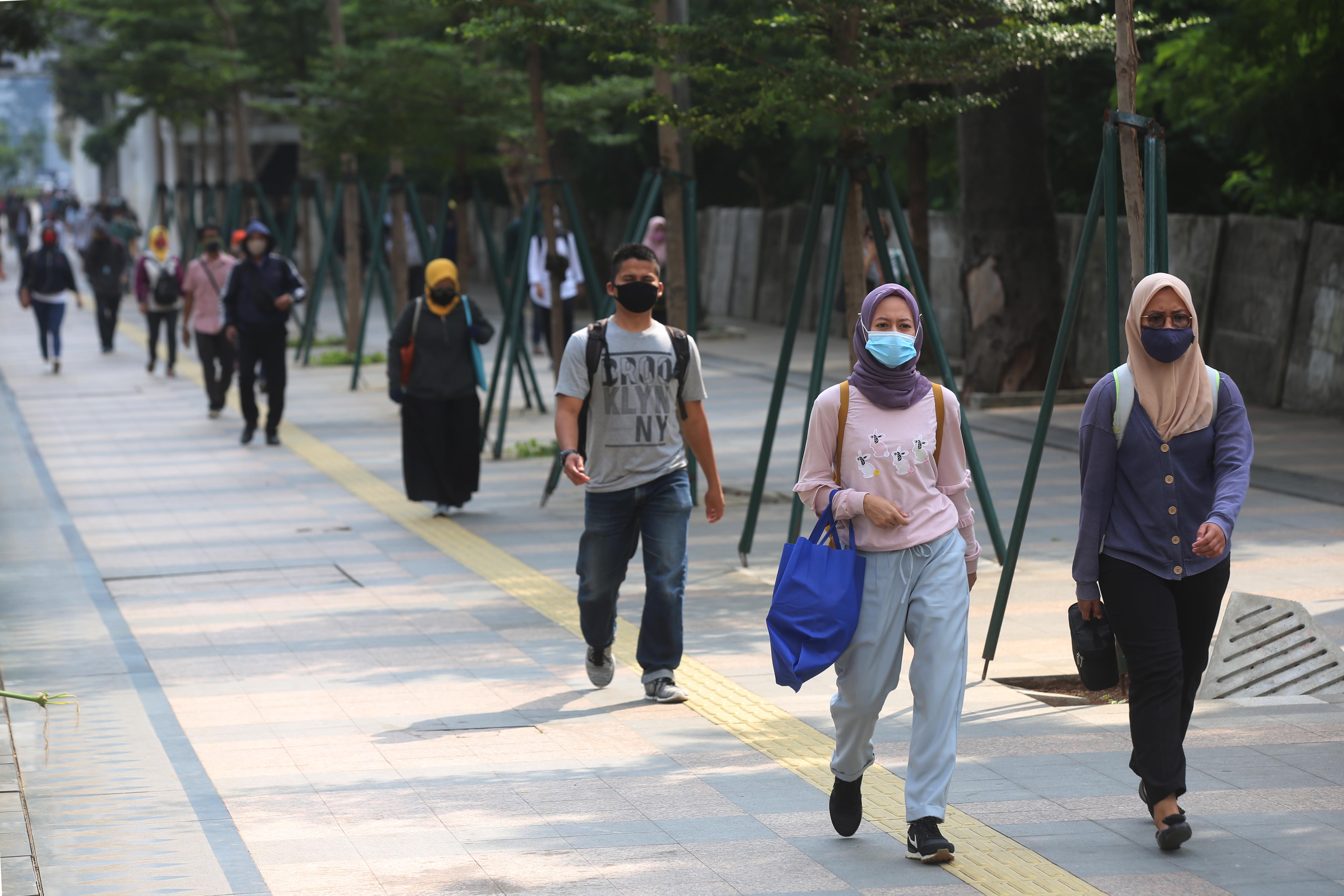 Pekerja menggunakan masker saat kembali beraktivitas di kantor pada masa PSBB transisi di jakarta