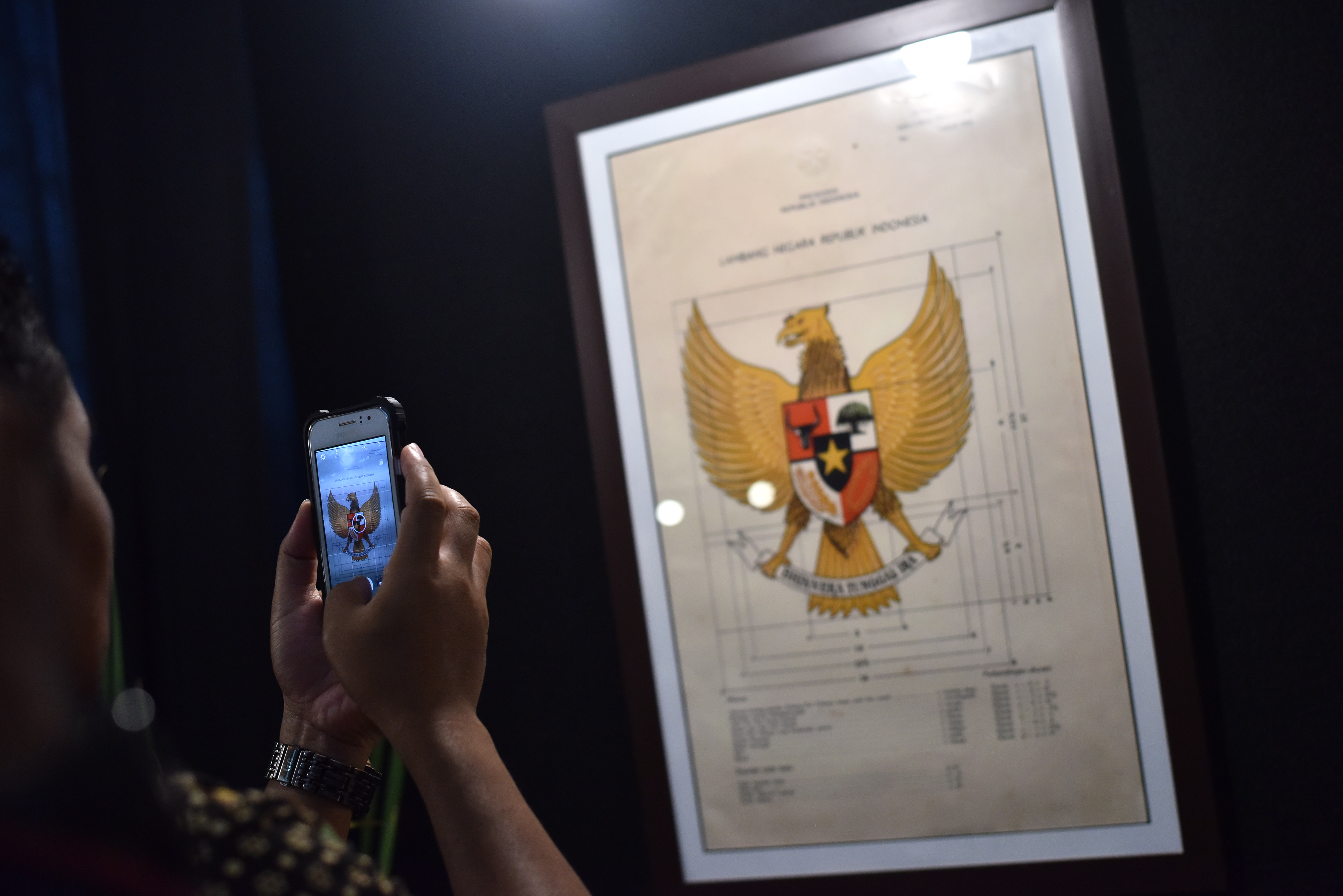 Seorang pengunjung museum nasional tengah memotret lambang negara Garuda Pancasila