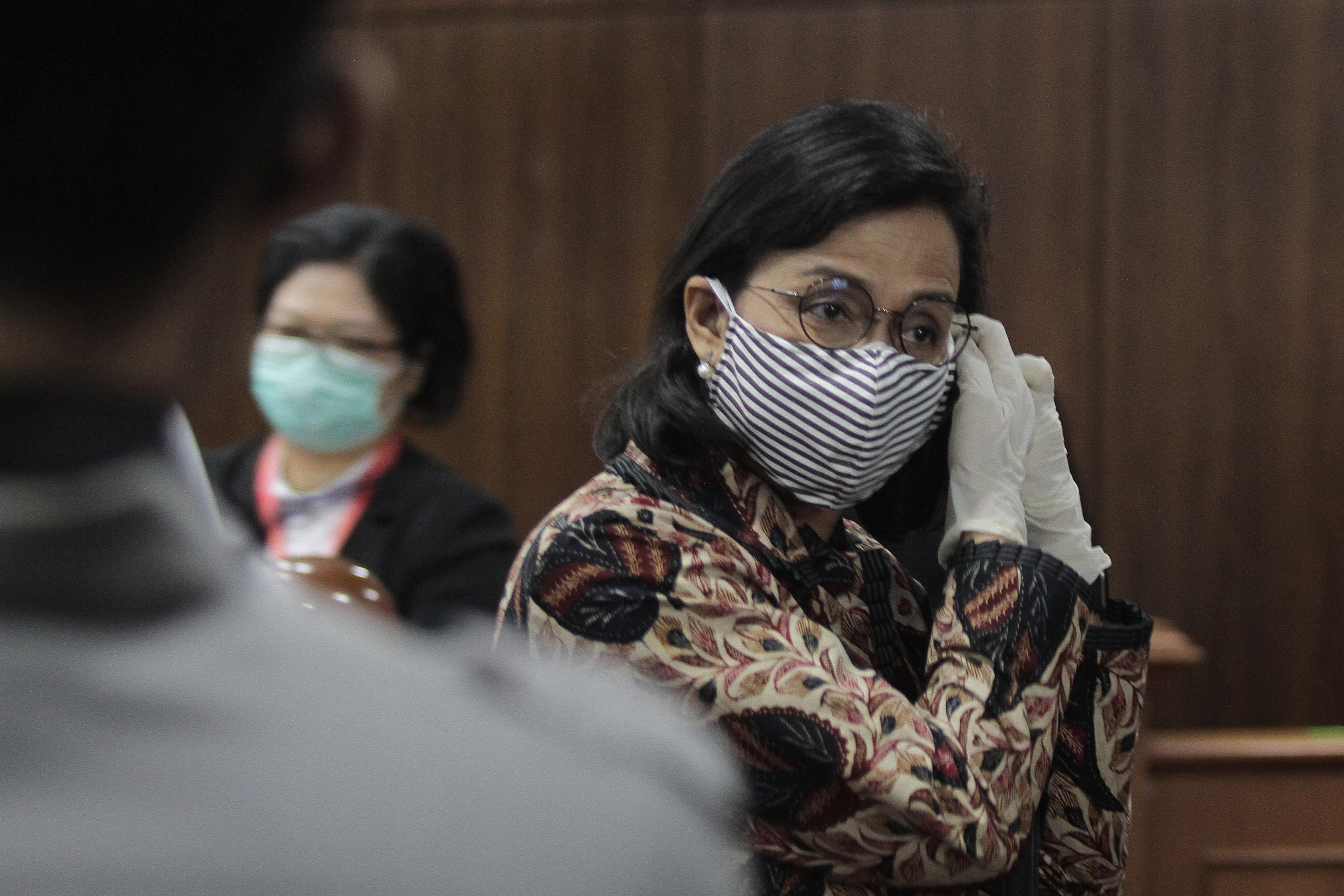 Menteri Keuangan Sri Mulyani membetulkan masker saat menghadiri sidang di Mahkamah Konstitusi.