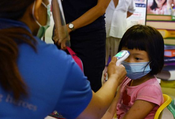Seorang guru di Singapura mengecek suhu tubuh anak murid sebelum memulai pelajaran di kelas. Sekolah mulai dibuka 2 Juni 2020. 