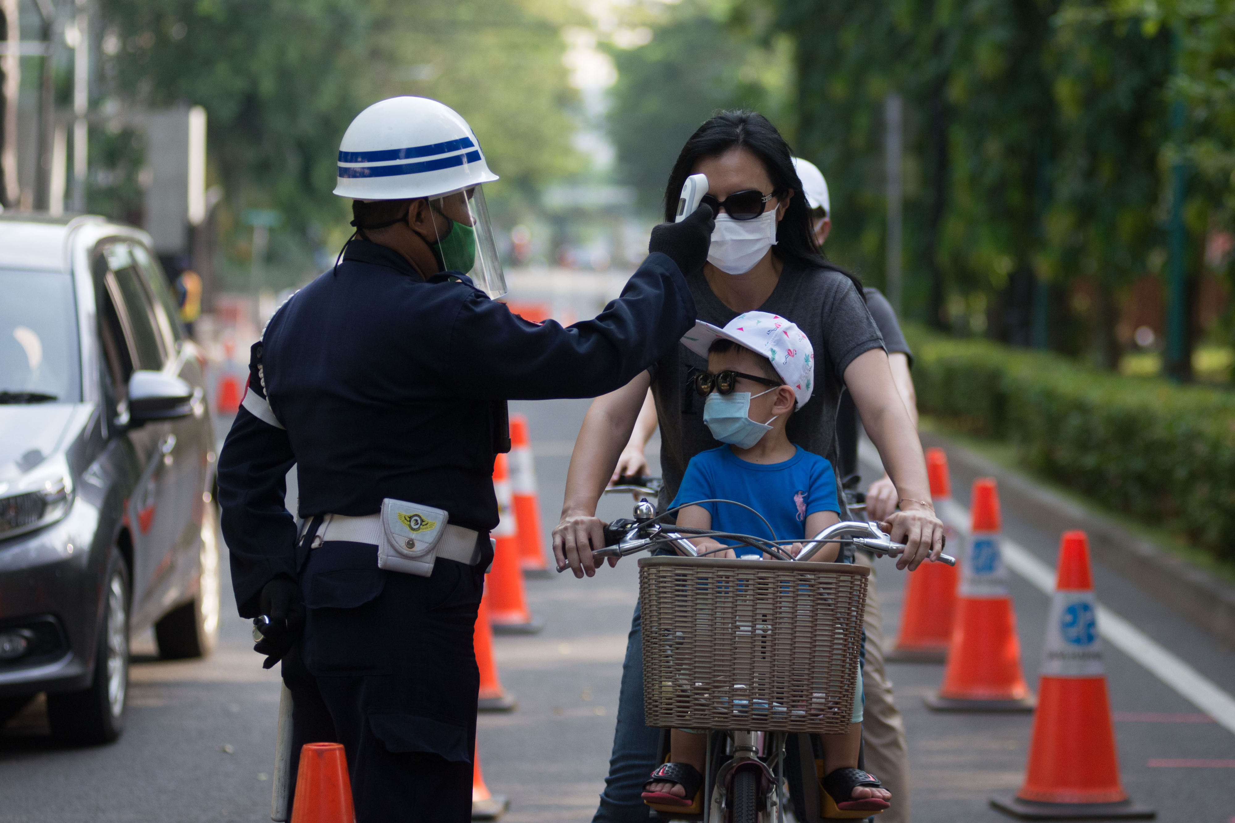 Seorang ibu bersama anaknya diperiksa suhu sebelum memasuki kawasan GBK
