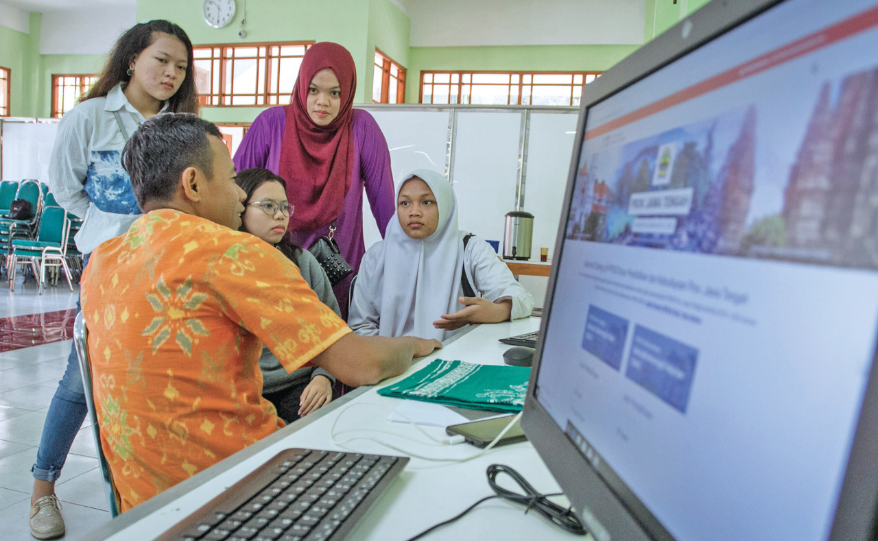 Siswa dan wali murid berkonsultasi dengan petugas pusat layanan informasi penerimaan peserta didik baru (PPDB) di SMA 7 Solo, Jawa Tengah.