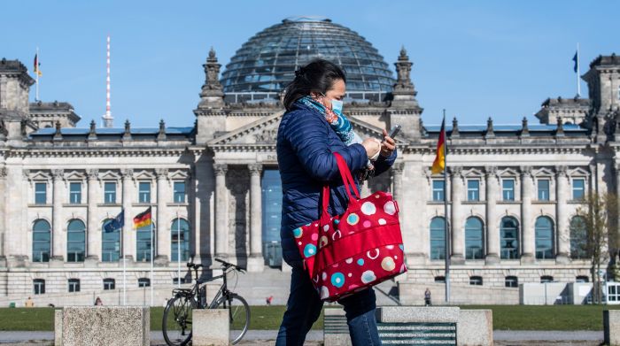 Seorang warga mengenakan masker melintas di depan gedung parlemen Jerman di Berlin.  