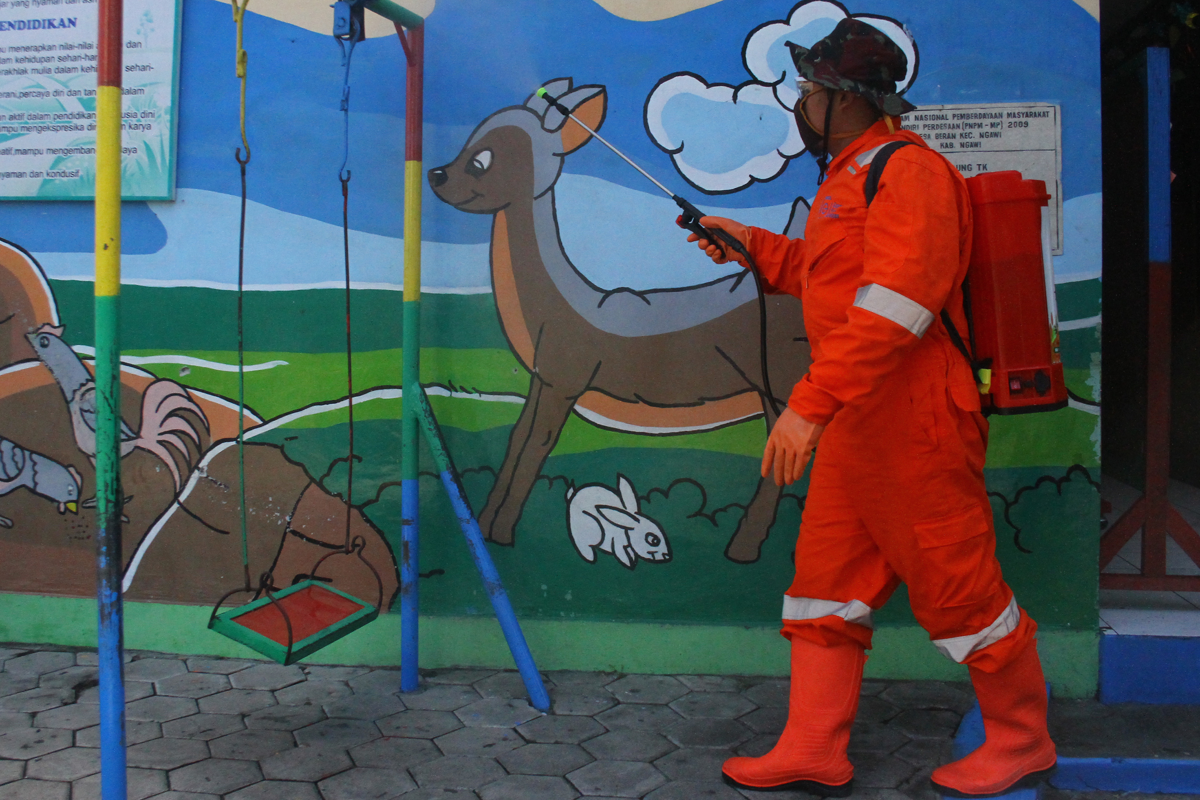 Relawan menyemprotkan cairan disinfektan di sebuah sekolah di Ngawi, Jawa Timu