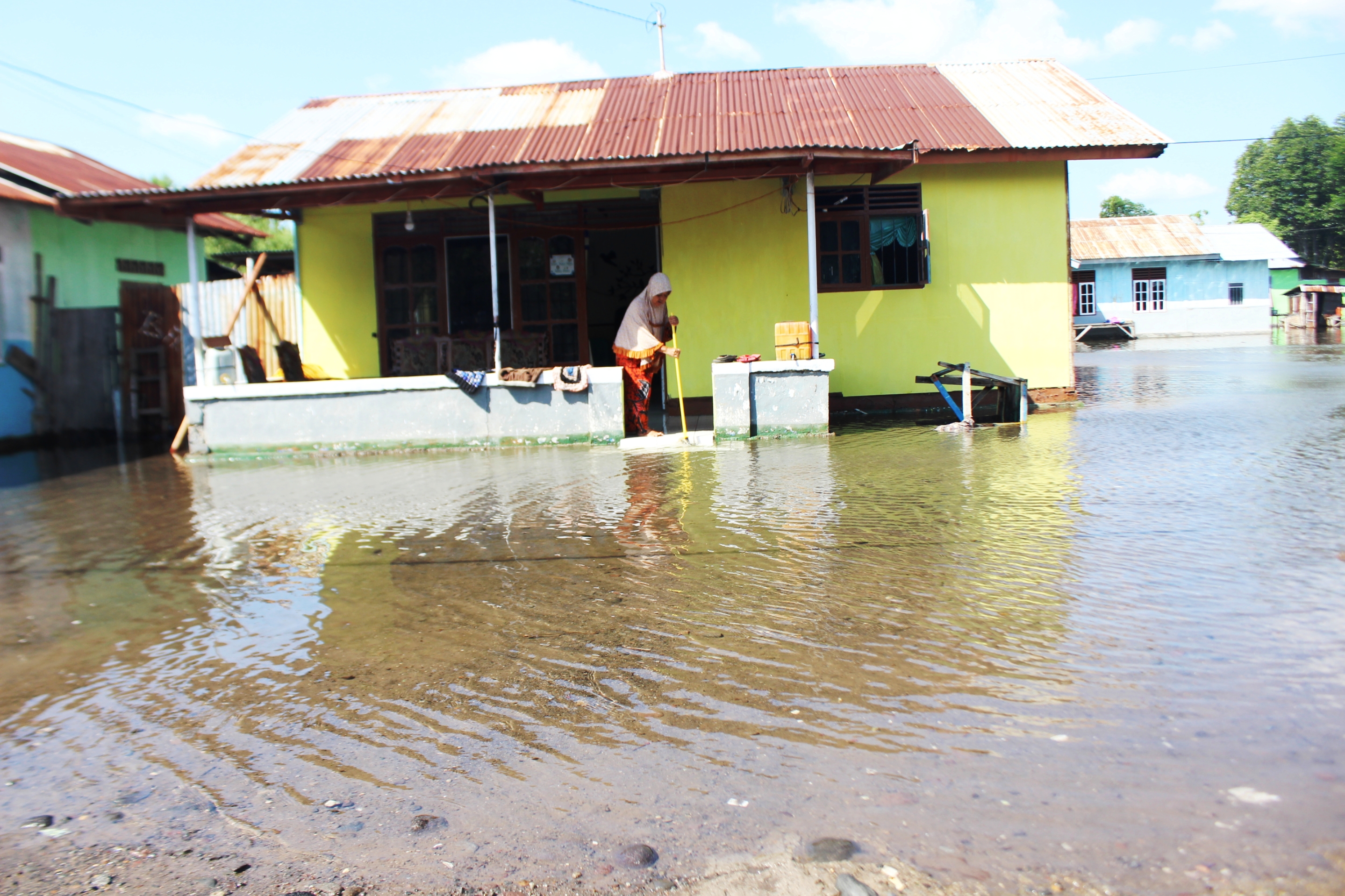 Salah satu warga sedang membersihkan rumahnya akibat kemasukan air laut atau banjir rob, Sabtu (6/6). 