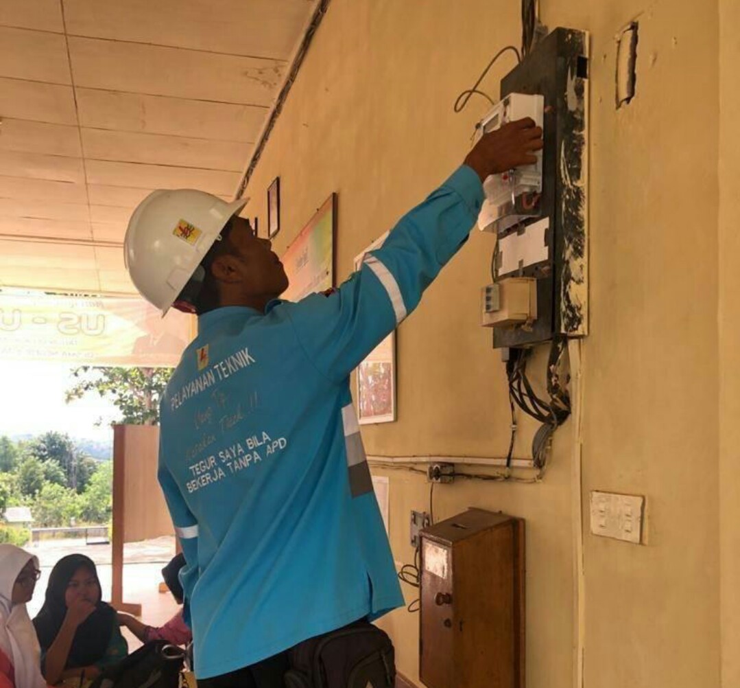 Petugas PLN sedang mencatat meteran pemakaian listrik di rumah warga.