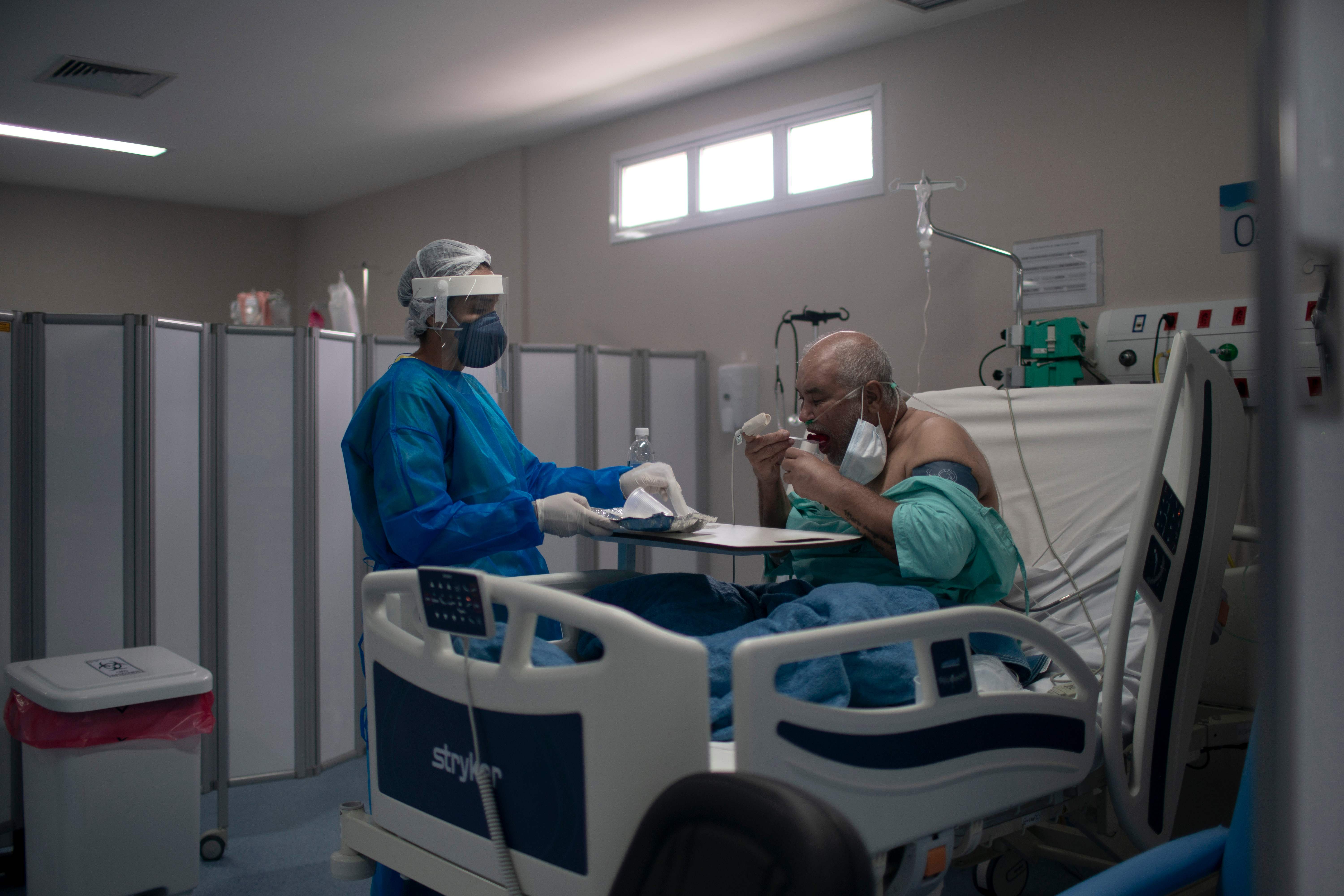  Seorang perawat memberikan makanan ke pasien covid-19 di bangsal ICU di di RSU Dokter Ernesto Che Guevara di kota Marica, Brasil, Jumat.