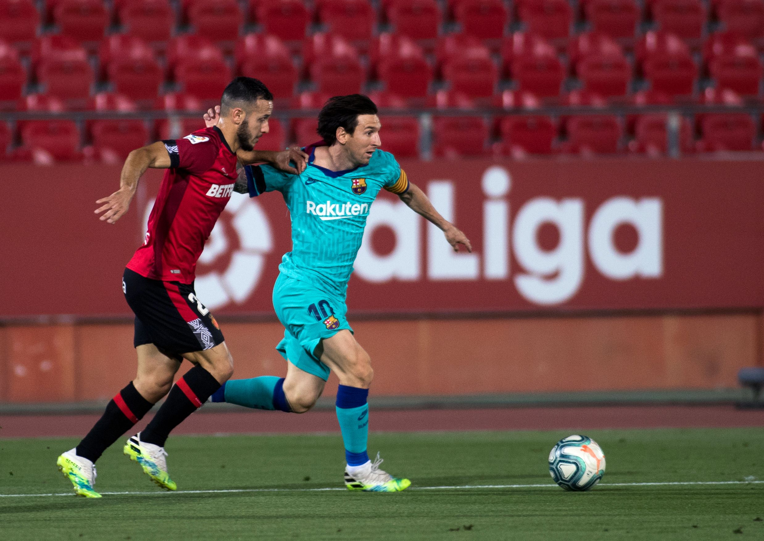 Lionel Messi (kanan) berebut bola dengan pemain Mallorca, Joan Sastre dalam lanjutan Liga Spanyol di Stadion Son Moix, Sabtu (13/6/2020)