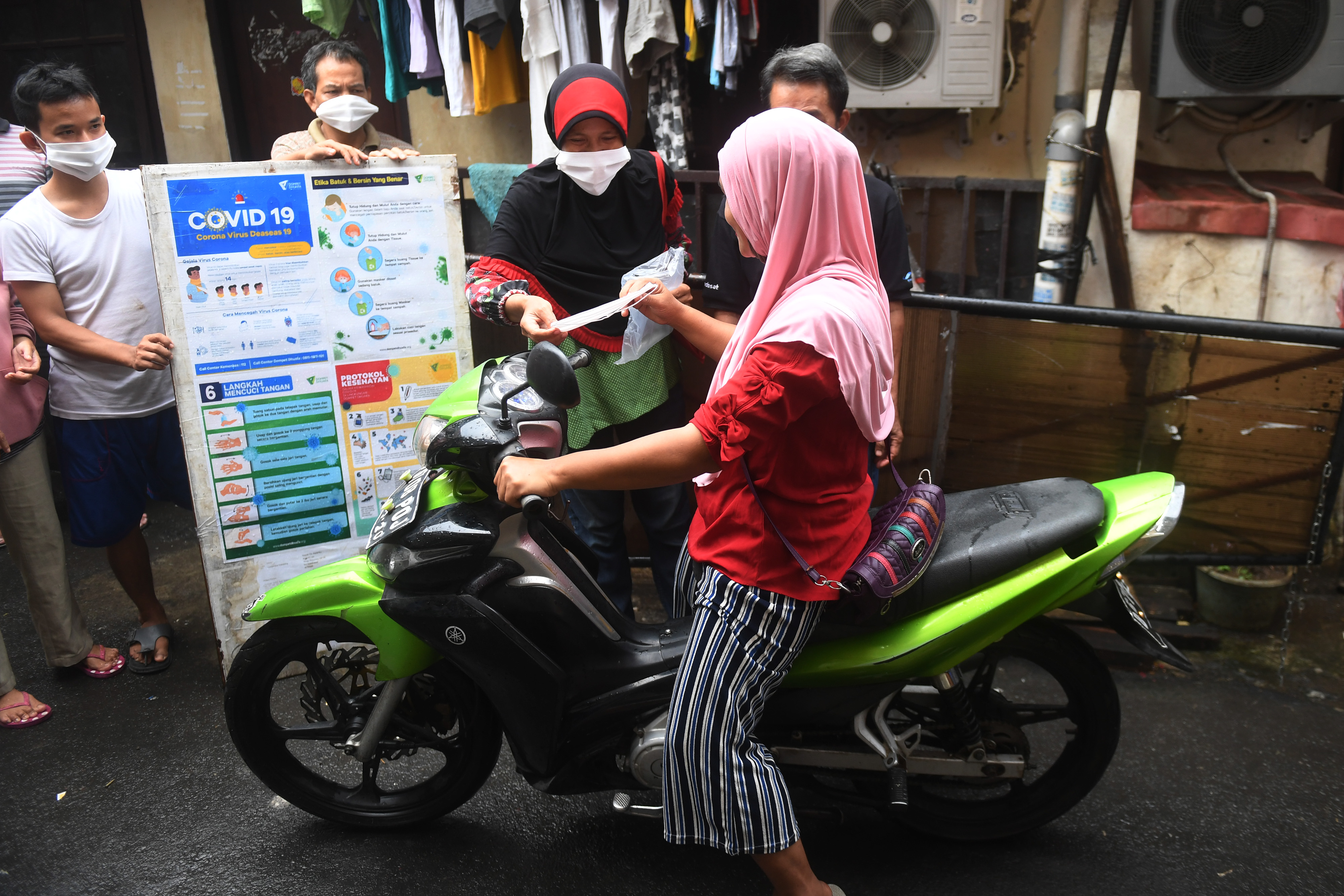  Warga memberikan masker kepada pengendara motor saat simulasi pelaksanaan PSBL di RT 05 RW 04, Petamburan
