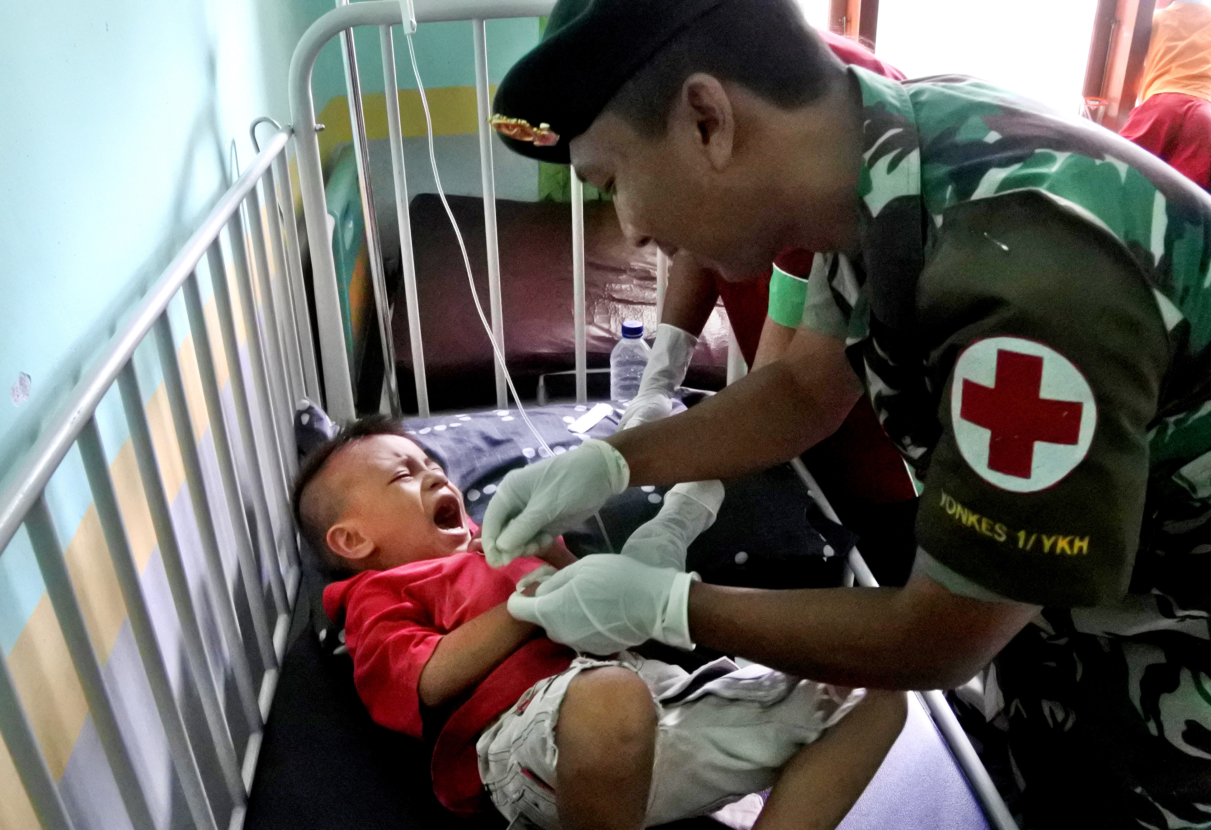 Anggota medis dari TNI-AD memasang jarum infus ke tangan pasien  DBD di puskesmas rawat inap Nita di Kecamatan Nita, Sikka.