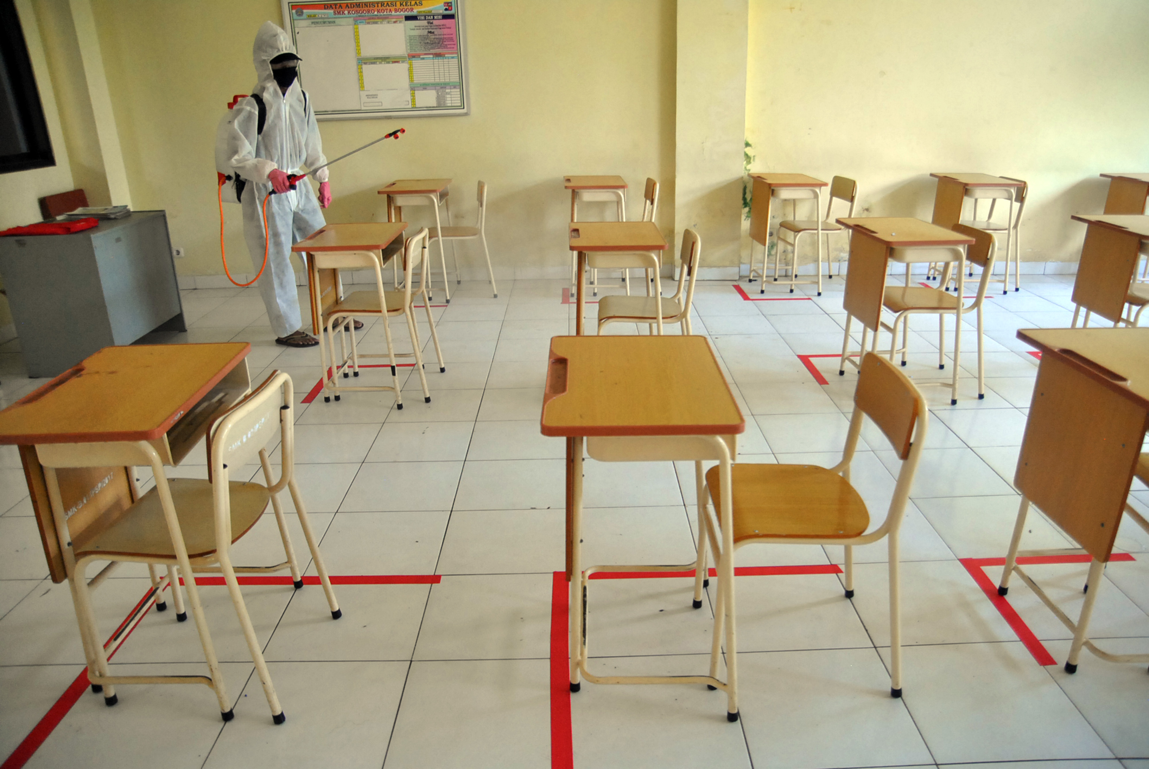 Petugas menyemprot cairan disinfektan di ruangan kelas SMK Kosgoro, Bogor.