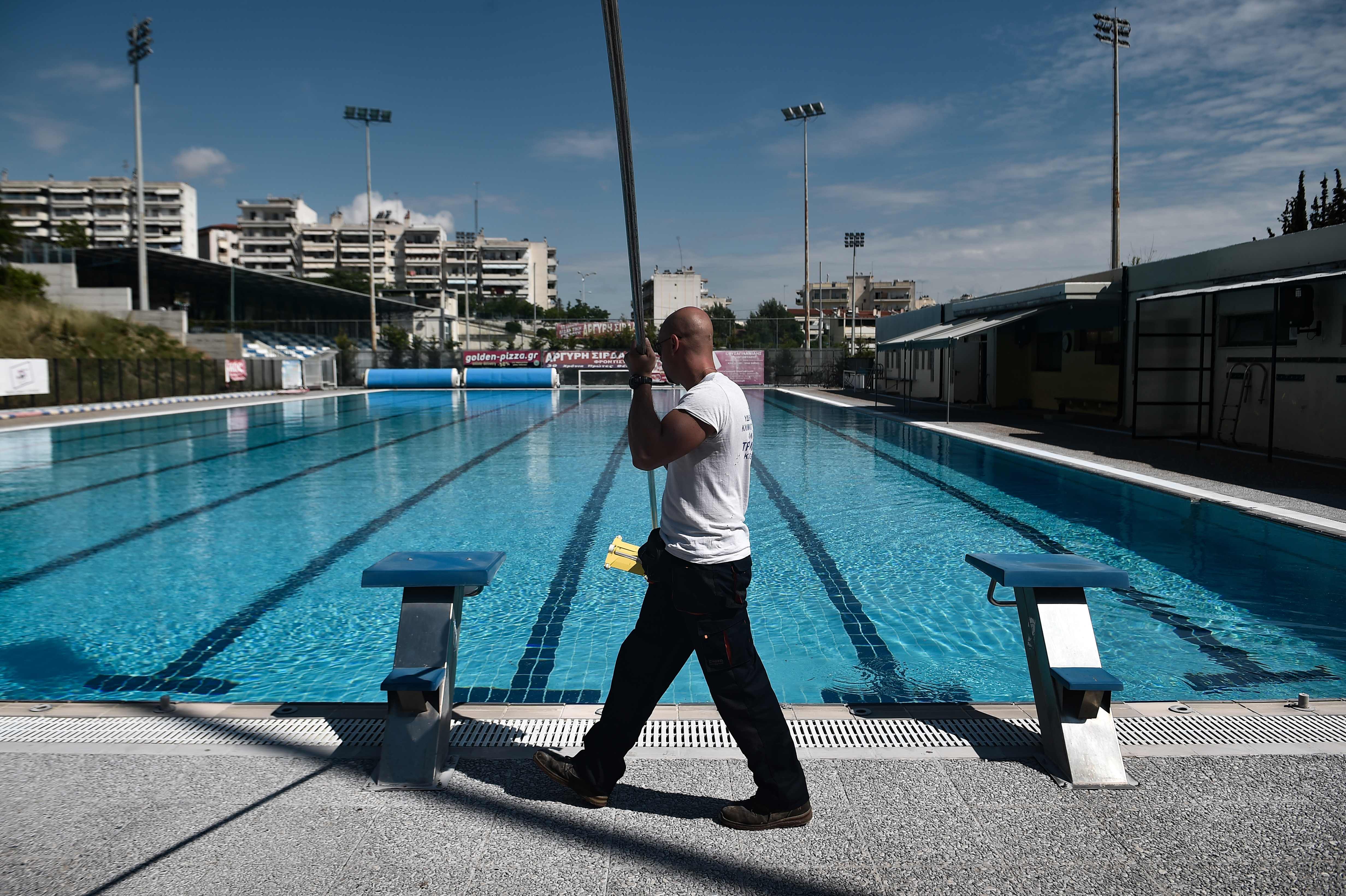 Seorang pekerja membersihkan kolam renang umum di Thessaloniki pada 1 Juni 2020 ketika lockdown sudah dicabut (1/6/2020)