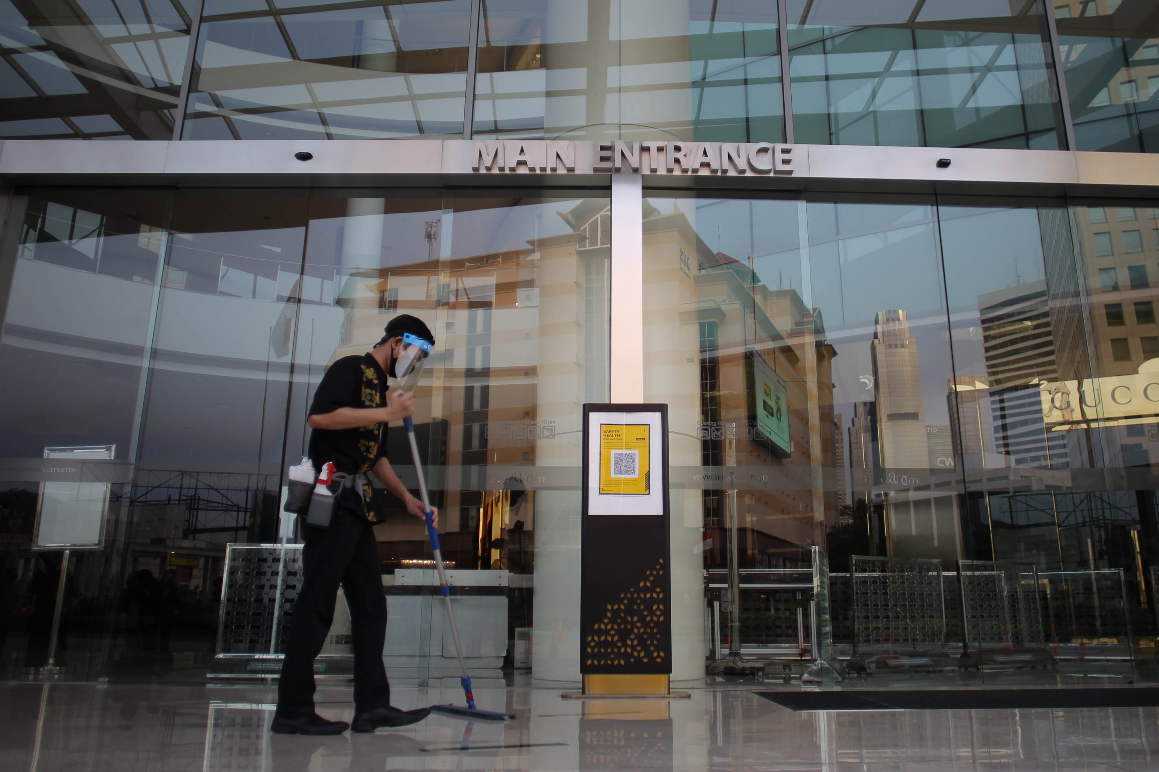 Petugas membersihkan area pintu masuk utama pusat perbelanjaan Senayan City, Jakarta, Sabtu (13/6). 