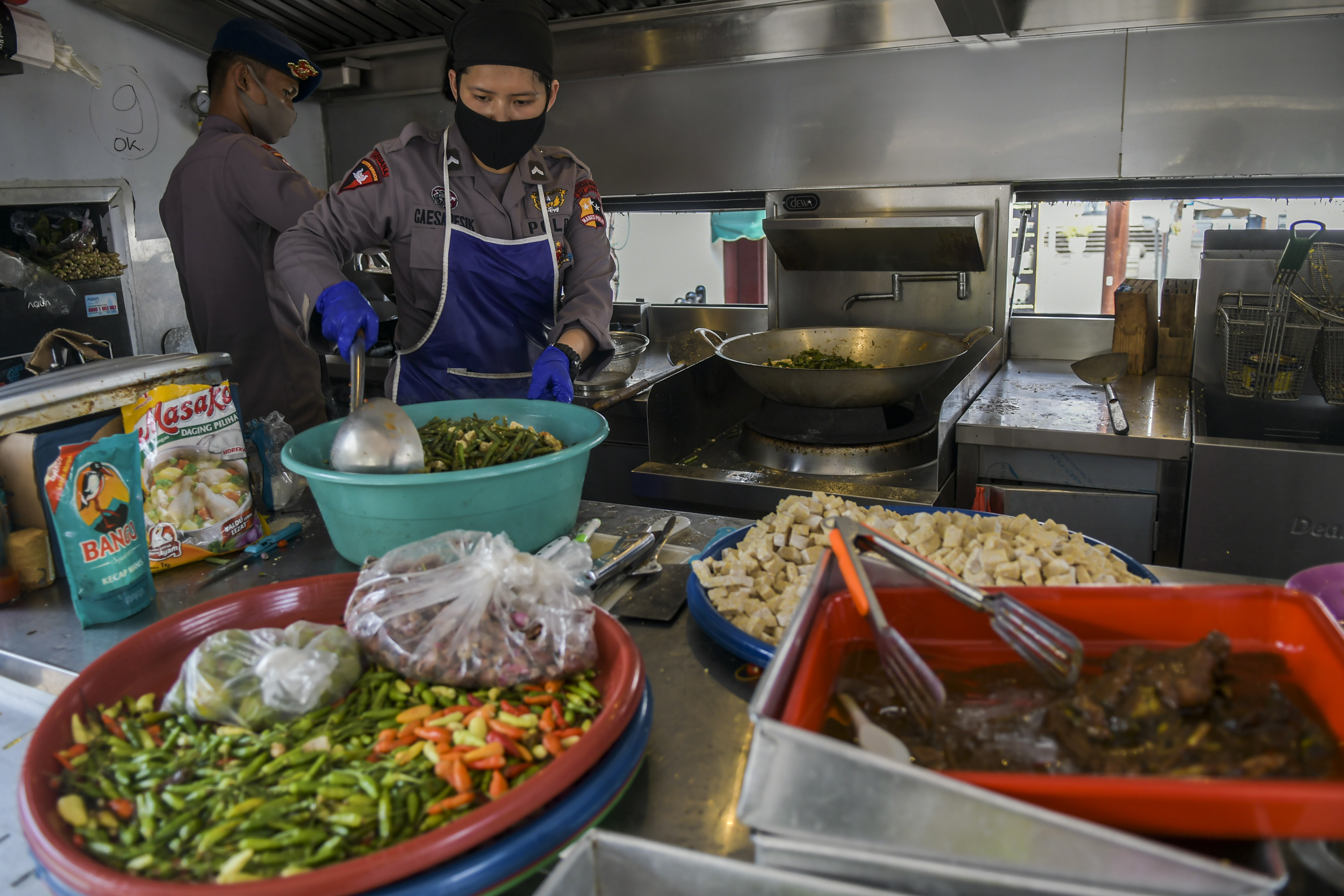 Petugas Kepolisian memasak di dapur umum di kawasan Kota Tua, Jakarta, Sabtu (18/4).