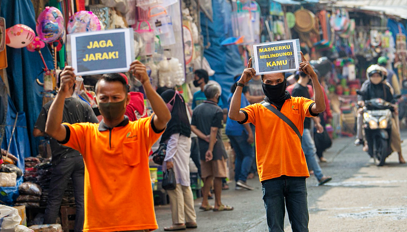 Petugas pengelola pasar berkampanye pencegahan COVID-19 dengan membawa poster berisi pesan di Pasar Jatinegara, Jakarta