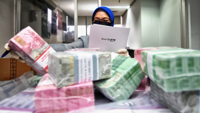 Seorang Petugas Teller PT Bank Tabungan Negara (Persero) Tbk. sedang menghitung uang kertas di Kantor Cabang Harmoni, Jakarta.