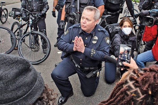 Kepala Kepolisian Bellevue, Steve Mylett berlutut saat meminta para demonstran menghentikan aksi di Bellevue, Amerika Serikat, (31/5).