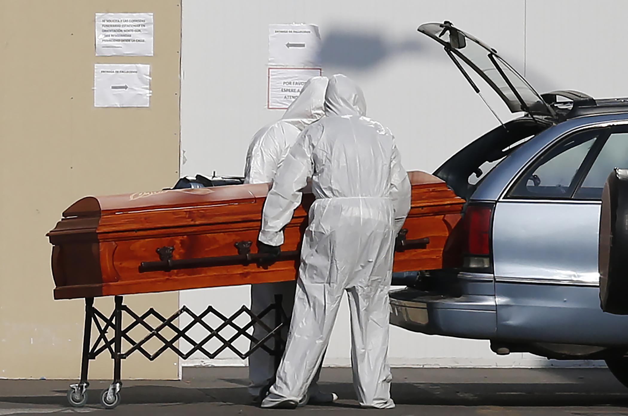 Petugas pemakaman memasukkan peti jenazah yang meninggal karena covid-19 ke dalam mobil