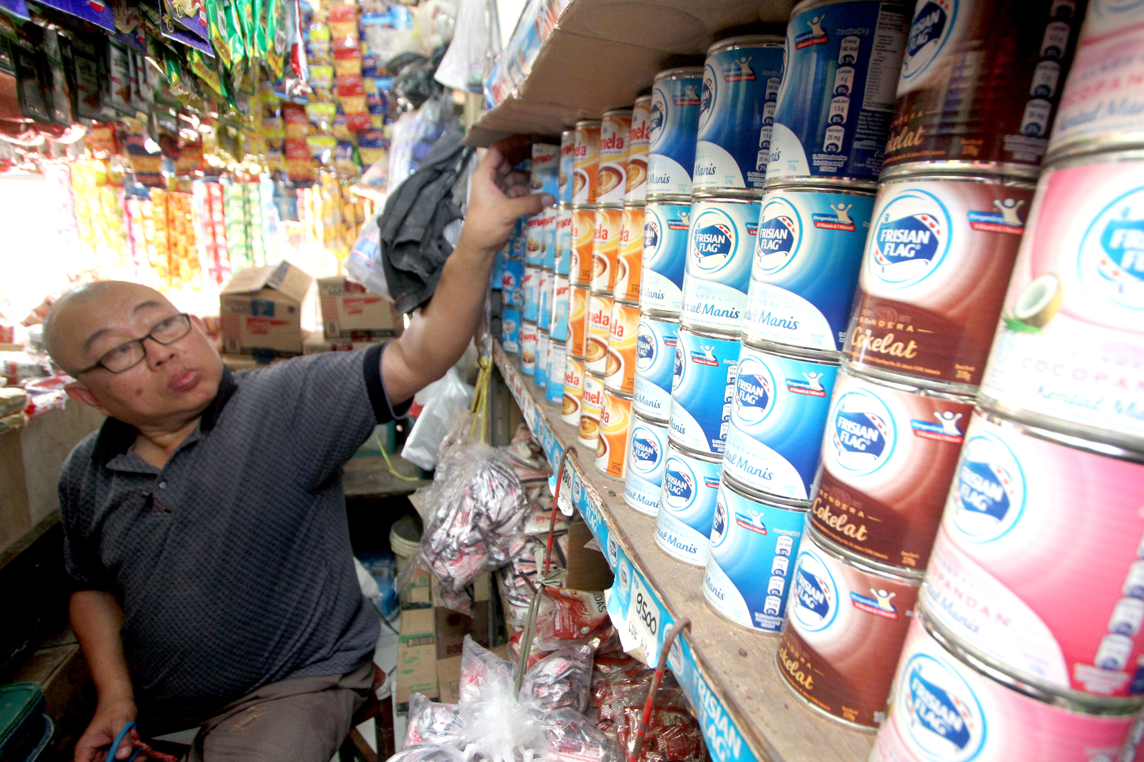 Pedagang menunjukkan produk susu kental manis kemasan yang dijual, di agen grosir miliknya di Cibinong, Kabupaten Bogor, Jawa Barat.