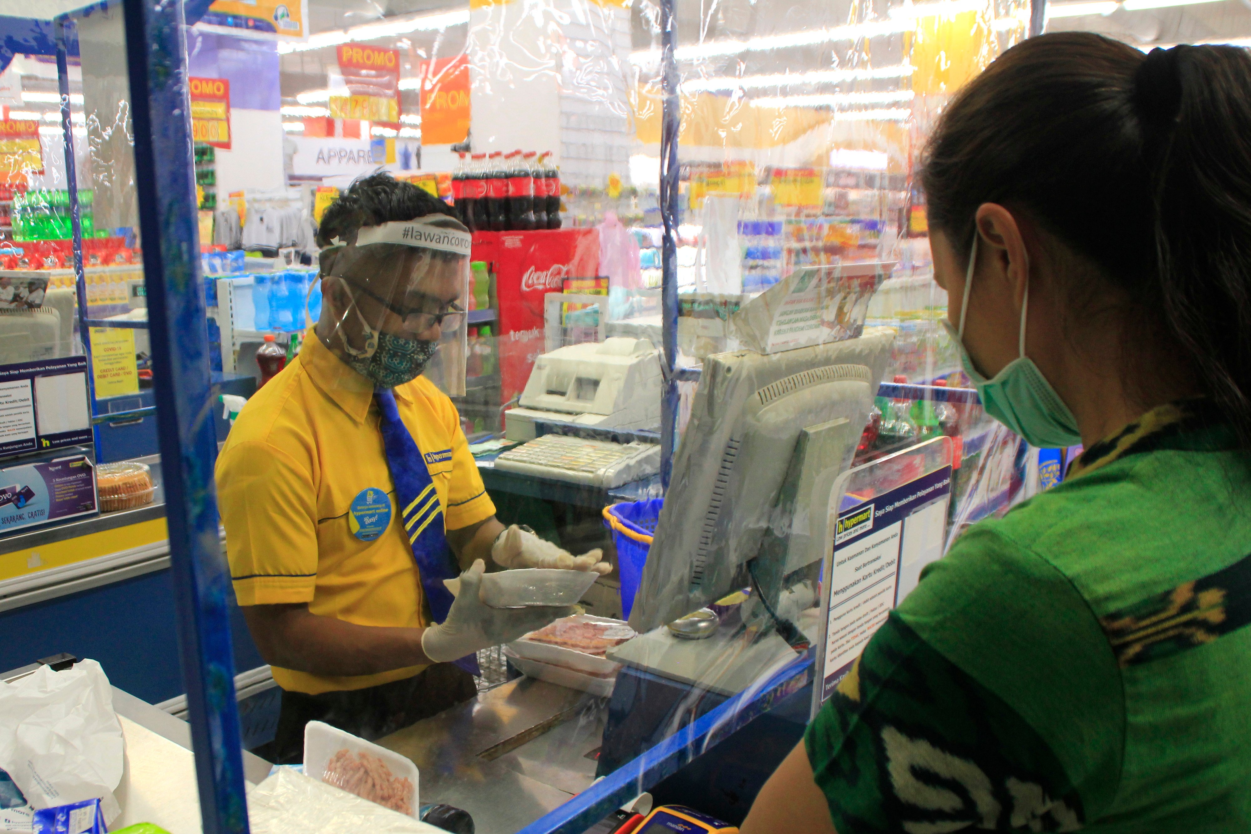 Petugas dengan bermasker dan berpelindung wajah melayani pembeli melakukan transaksi pembayaran di kasir toko di Kota Kupang, NTT.