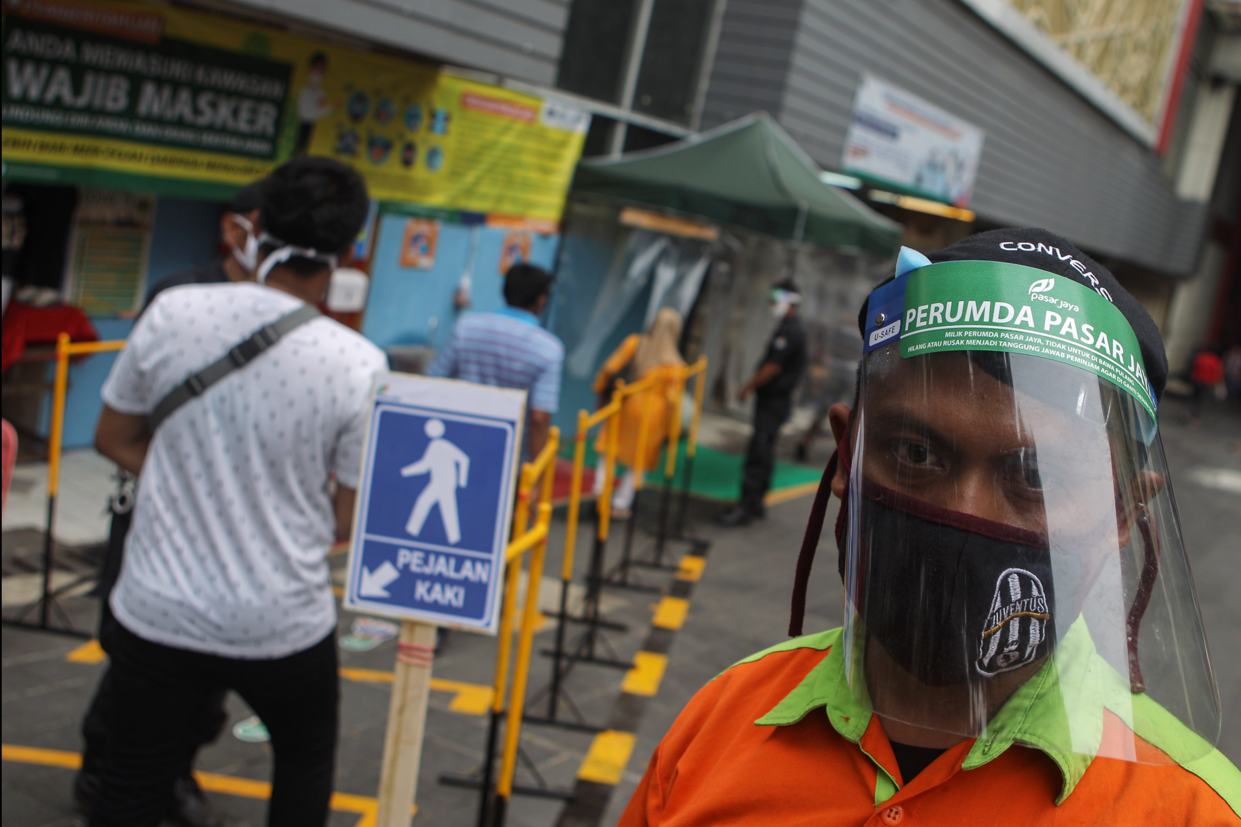 Petugas menggunakan pelindung wajah di pintu masuk pusat perbelanjaan Pasar Tanah Abang, Jakarta, Senin (15/06/2020)