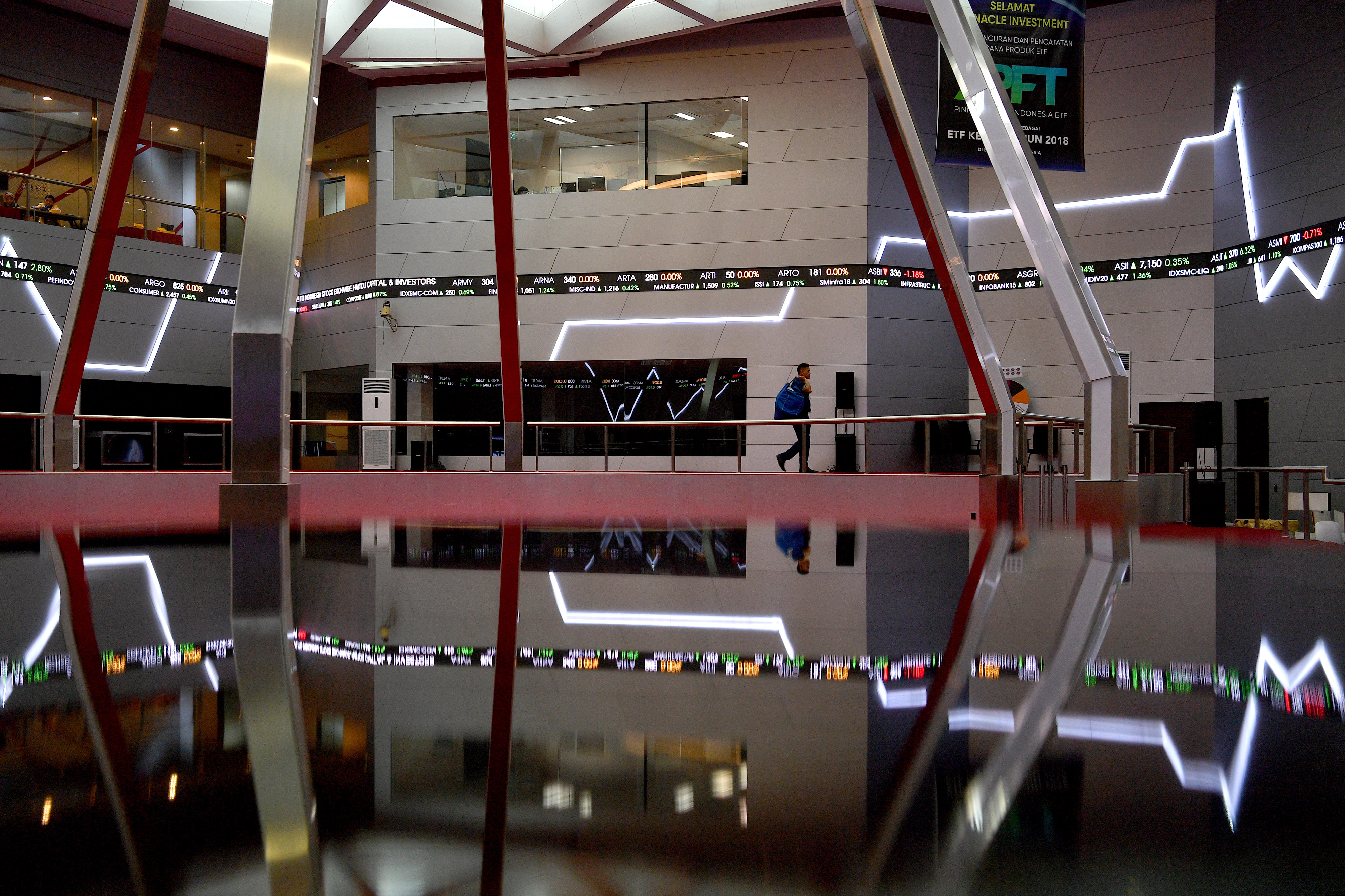 Karyawan melintas di bawah layar monitor pergerakan Indeks Harga Saham Gabungan (IHSG) di Bursa Efek Indonesia (BEI), Jakarta.