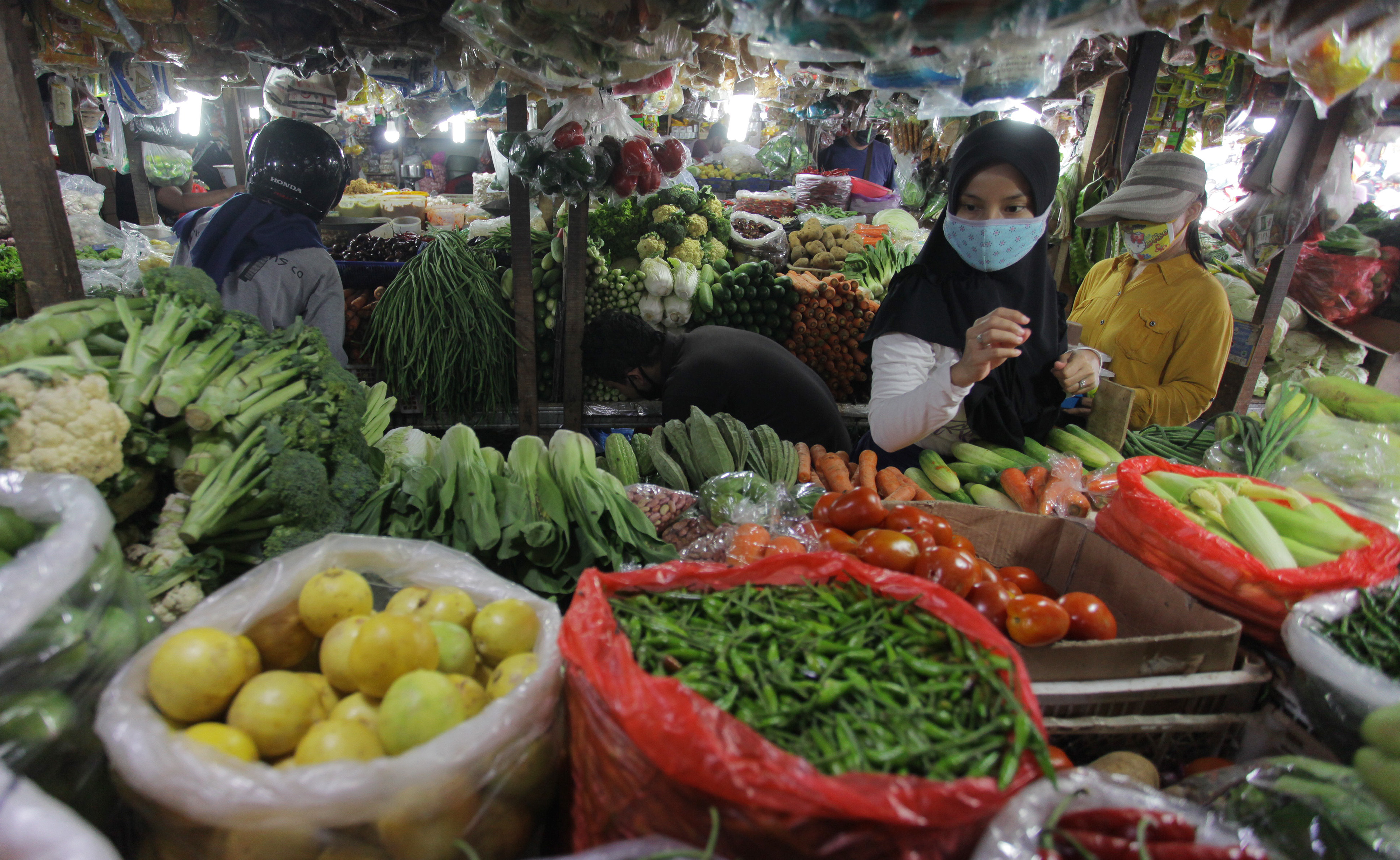 Warga dengan masker memilih sayuran di pasar tradisional Pondok Labu, Jakarta, Minggu (7/6).