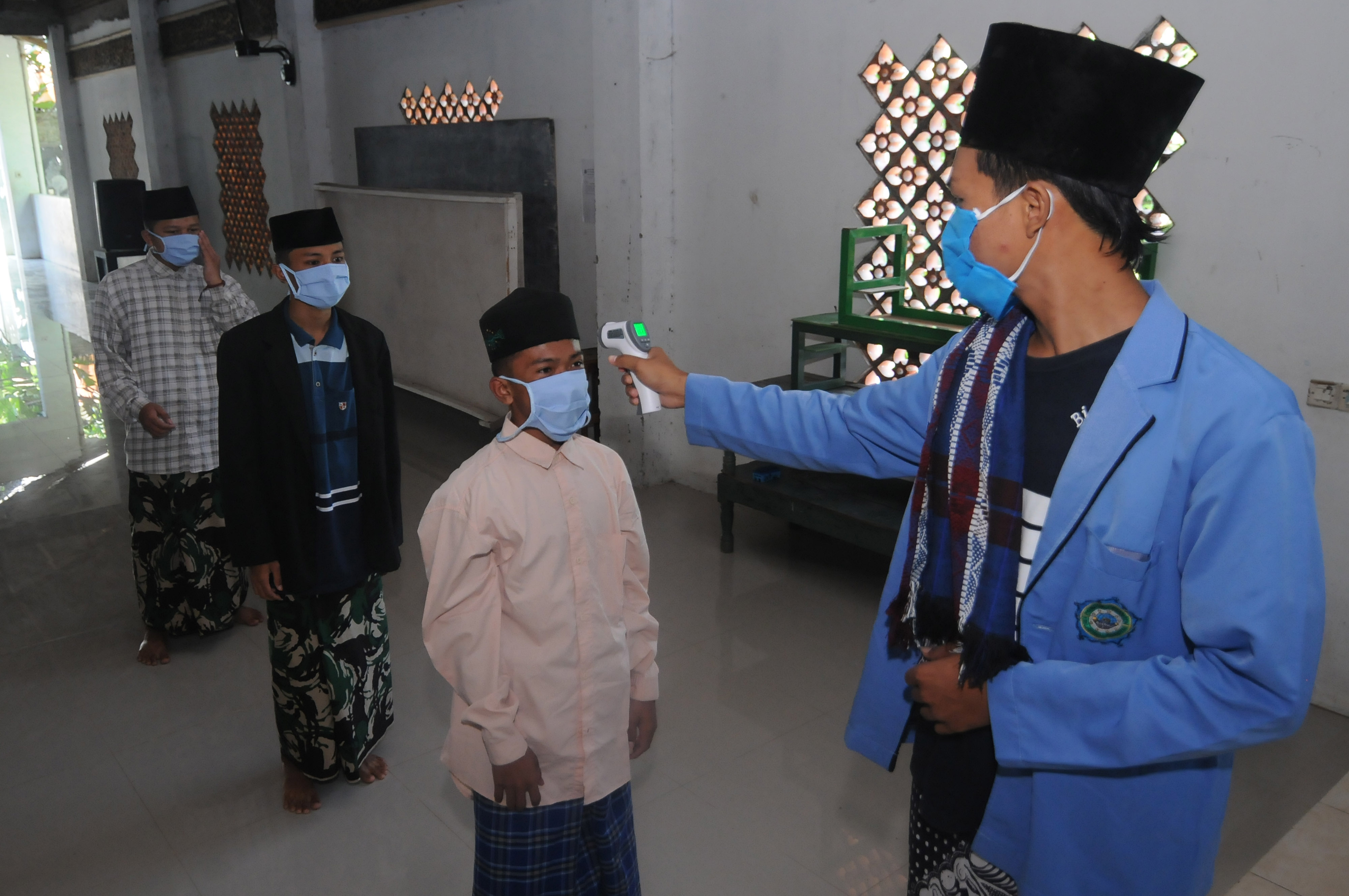 Seorang santri mengecek suhu tubuh para santri lainnya saat akan Shalat Dzuhur di Pondok Pesantren Nurul Hidayah Al Mubarokah, Boyolali