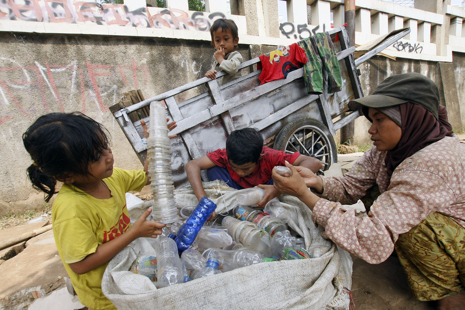 Wasniah bersama ketiga anaknya memilah barang bekas di pinggir Jalan Juanda, Depok.