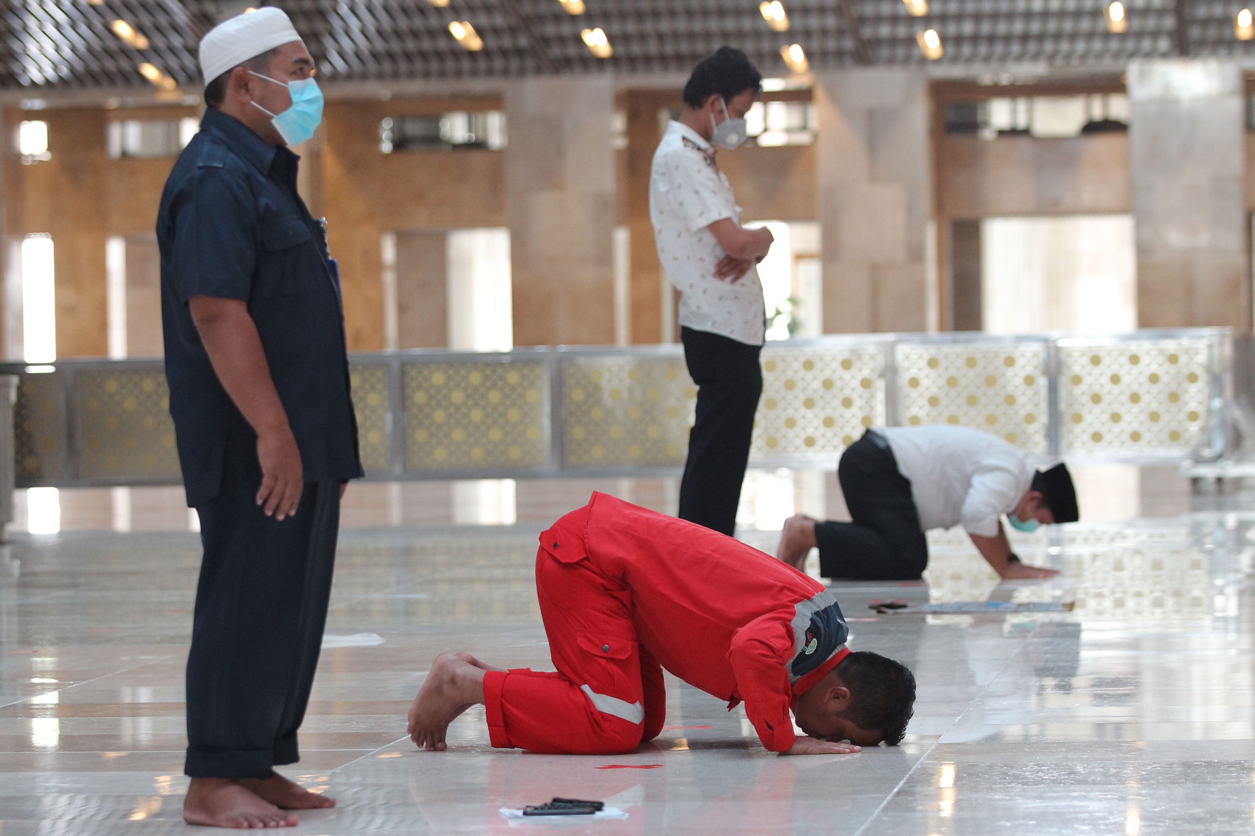 Jemaah mengenakan masker dan menjaga jarak fisik saat melaksanakan salat di masjid