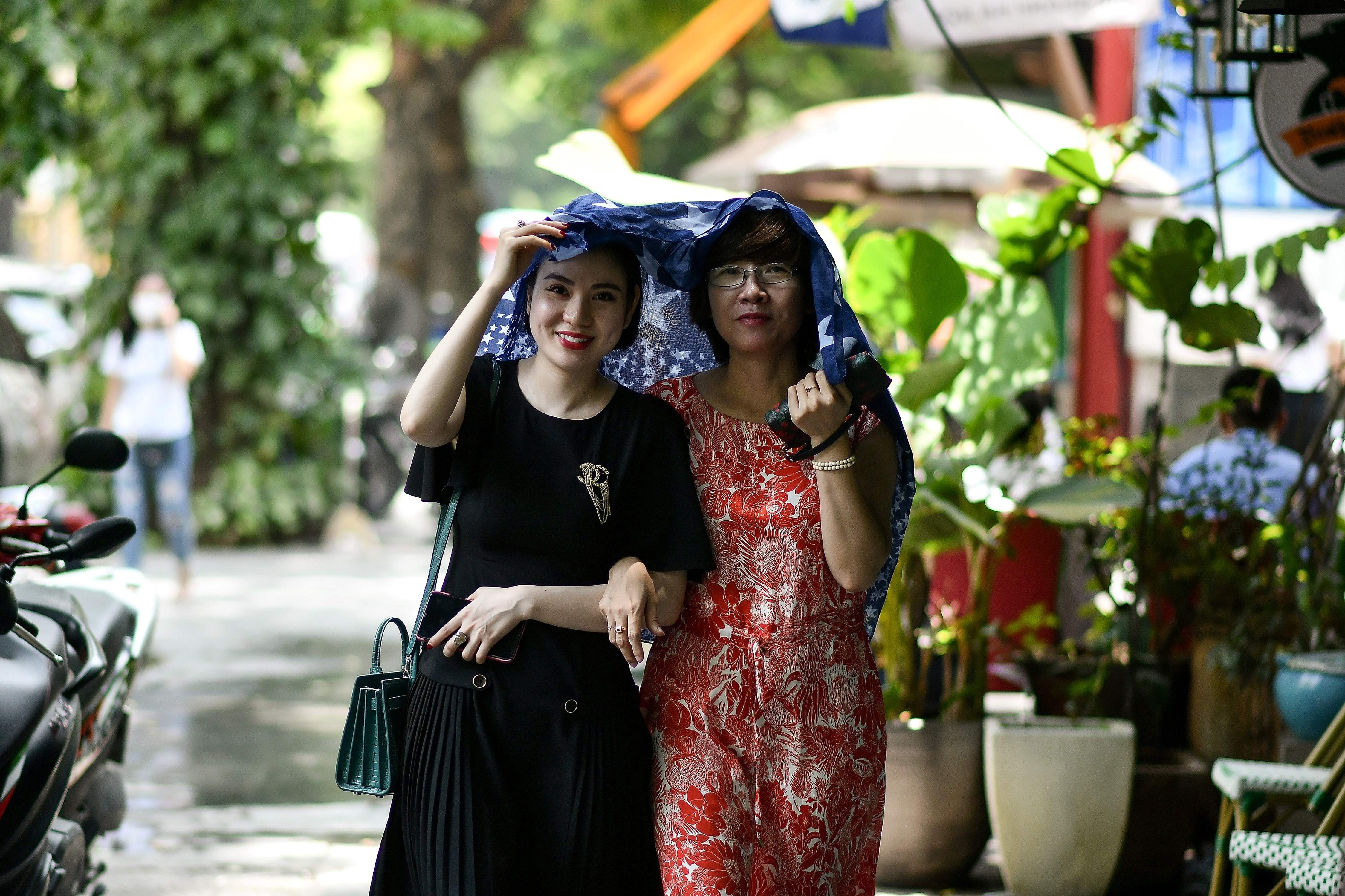 Dua wanita Vietnam tanpa memakai masker sedang berjalan-jalan di Hanoi (4/6/2020)