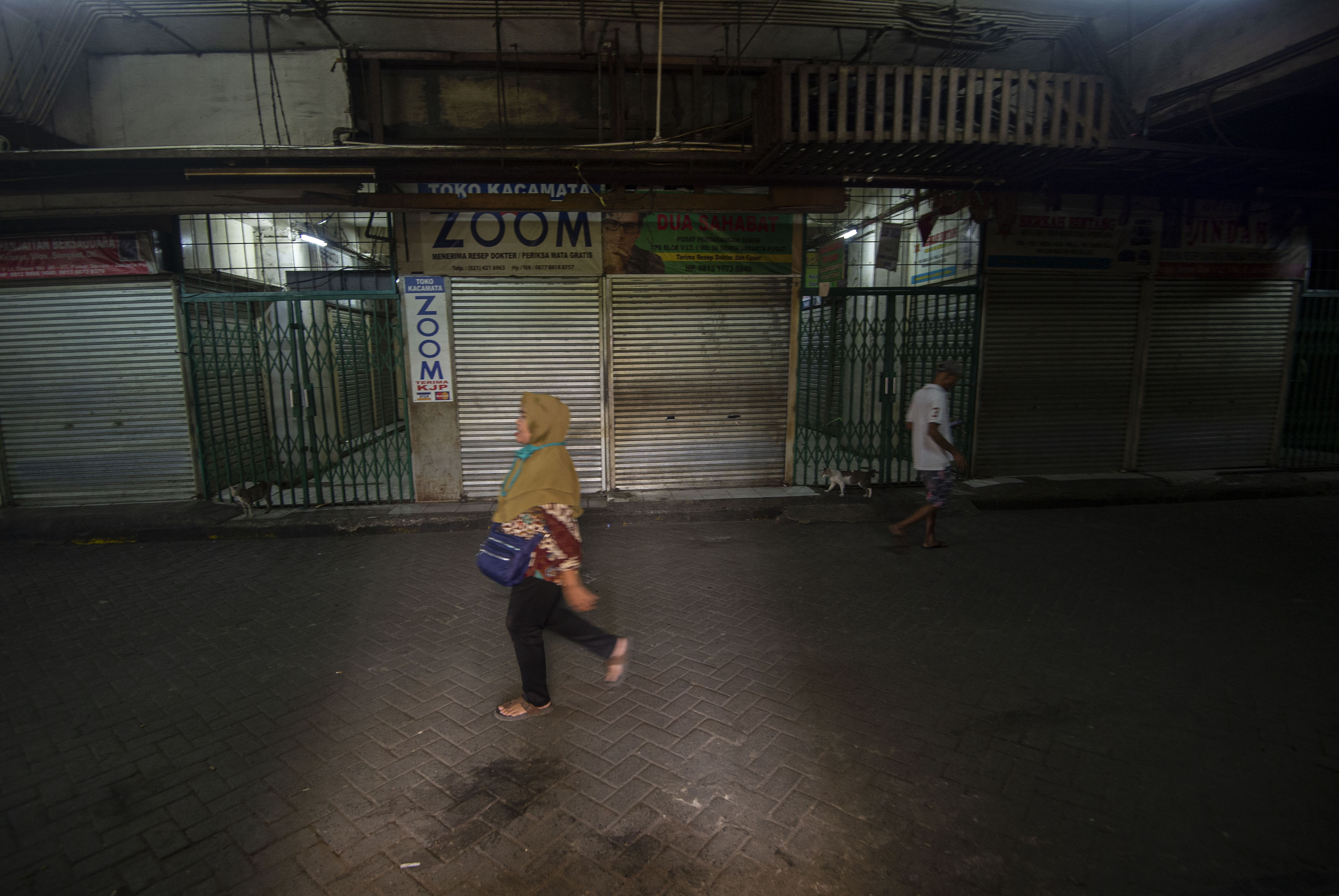 Warga melintasi kios di Blok V Pasar Senen, Jakarta, yang masih tutup.