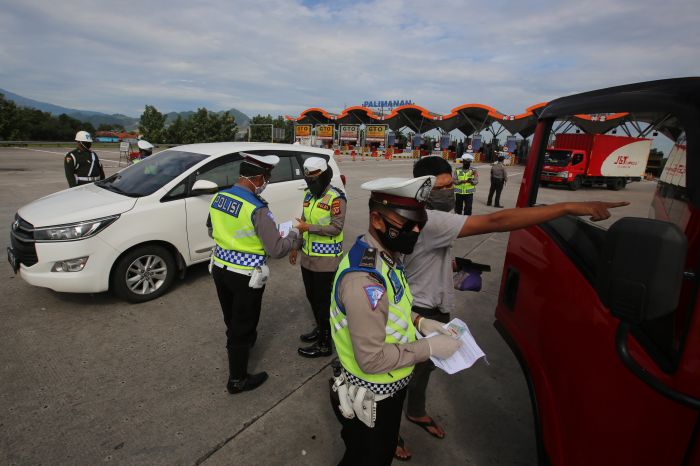 Petugas gabungan memeriksa SIKM pengendara agar bisa melintasi perbatasan wilayah.  